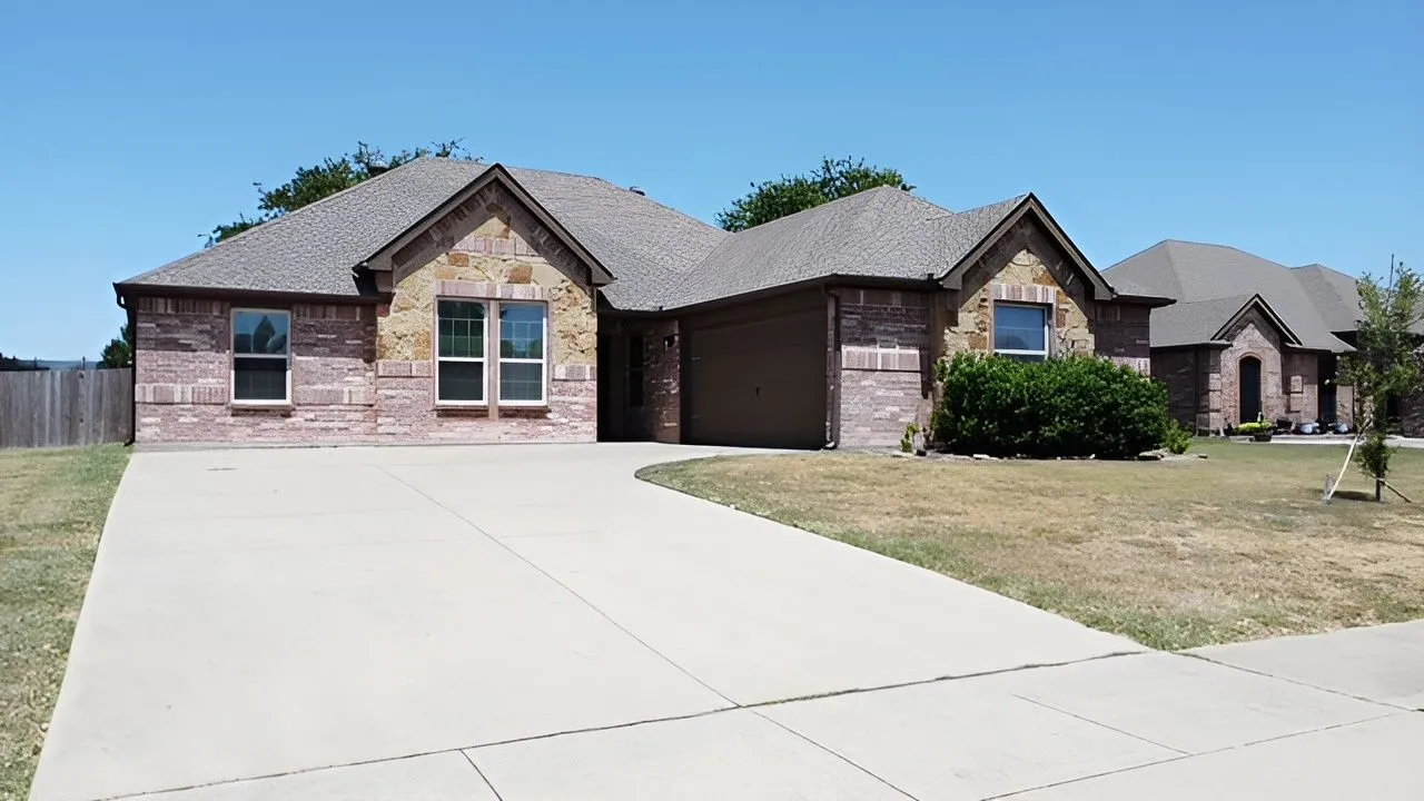 Brick and stone veneer exterior with a concrete driveway, attached garage, and pitched roof