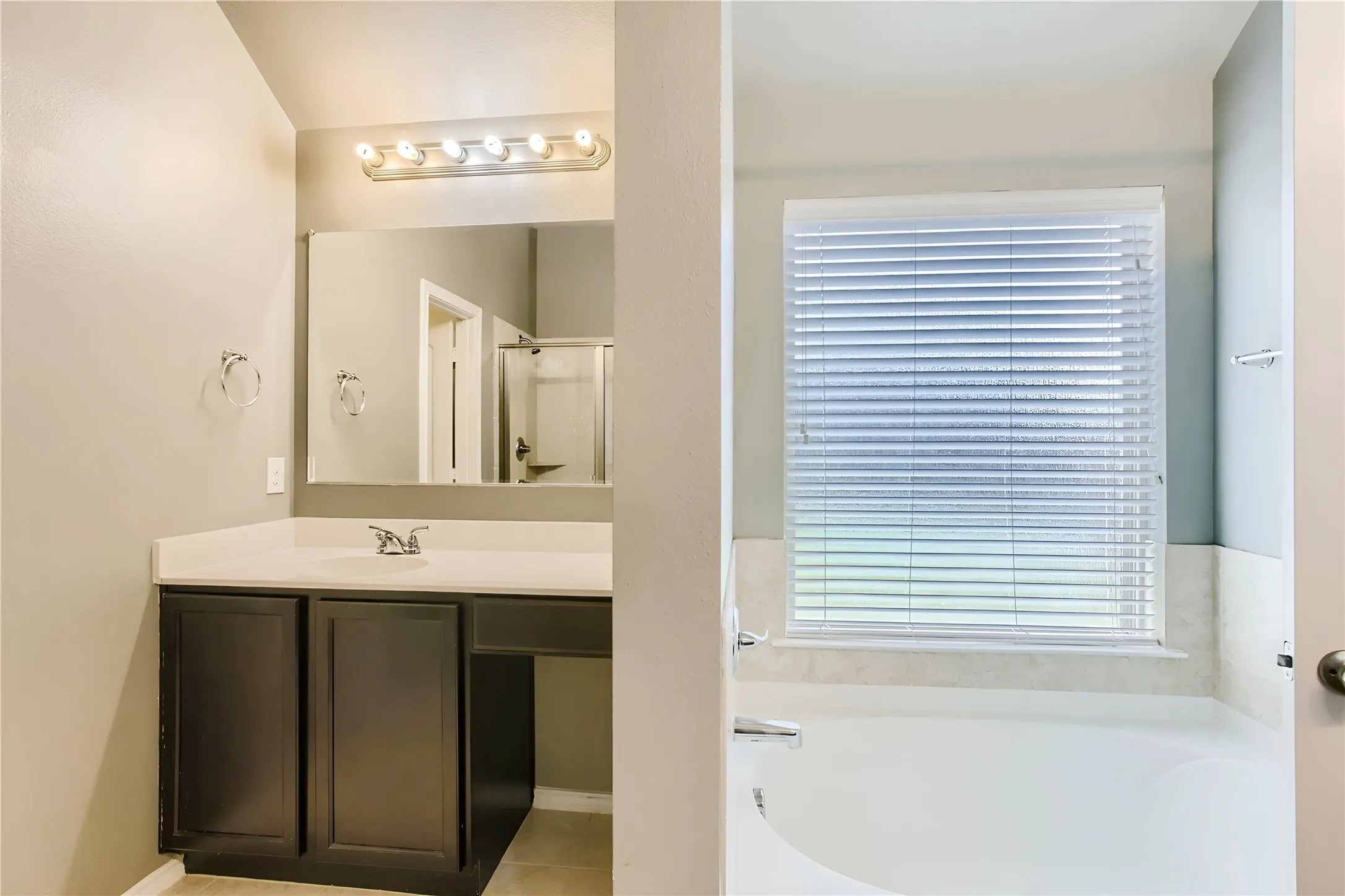 Vanity with dark wood-finish cabinetry, light-toned countertop, and undermount sink