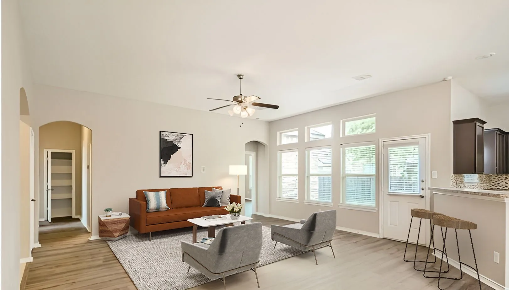 Wood-finish flooring, high ceilings, multiple windows, arched doorways, and a ceiling fan with integrated lighting