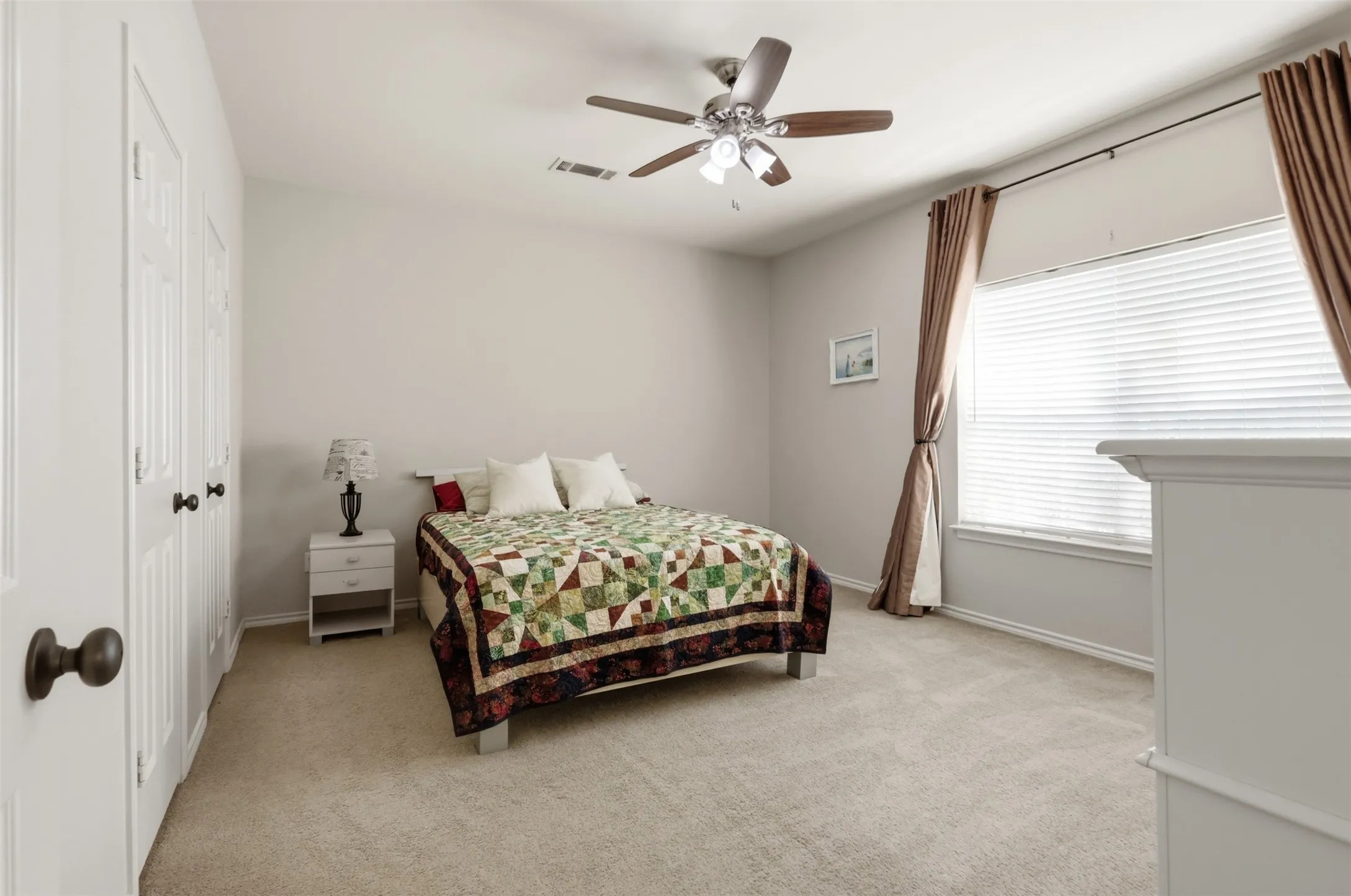 Secondary bedroom with large window and ceiling fan.