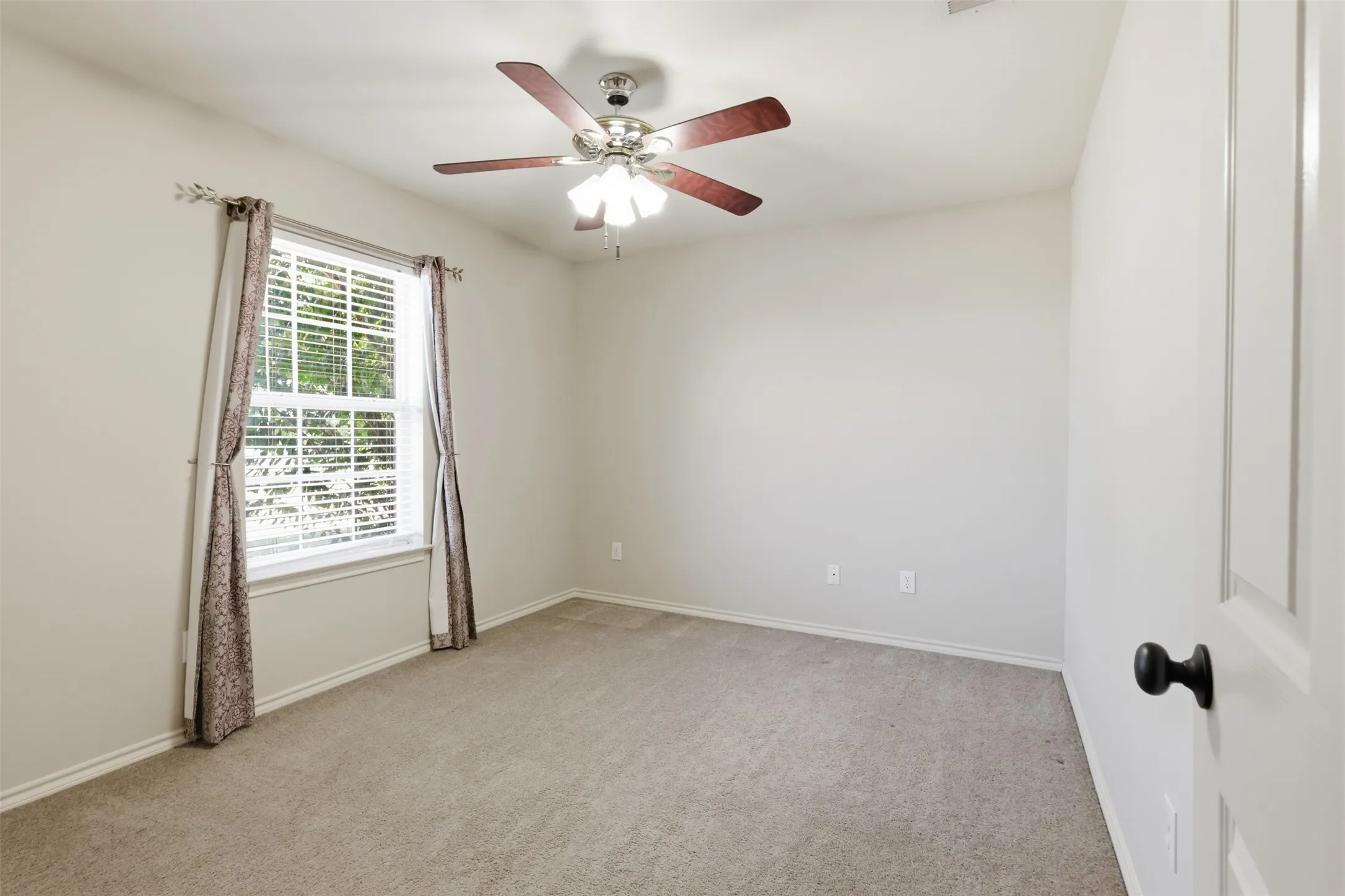 Third bedroom with large window and ceiling fan.
