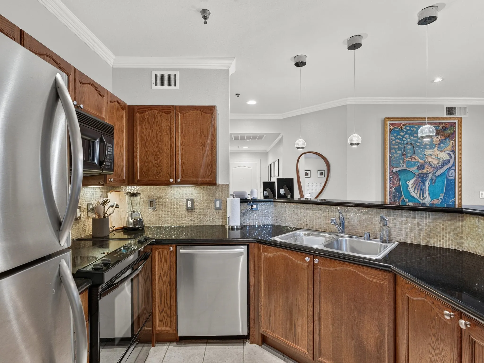 Stainless steel appliances, wood cabinetry, dark countertops, tile backsplash, and recessed lighting