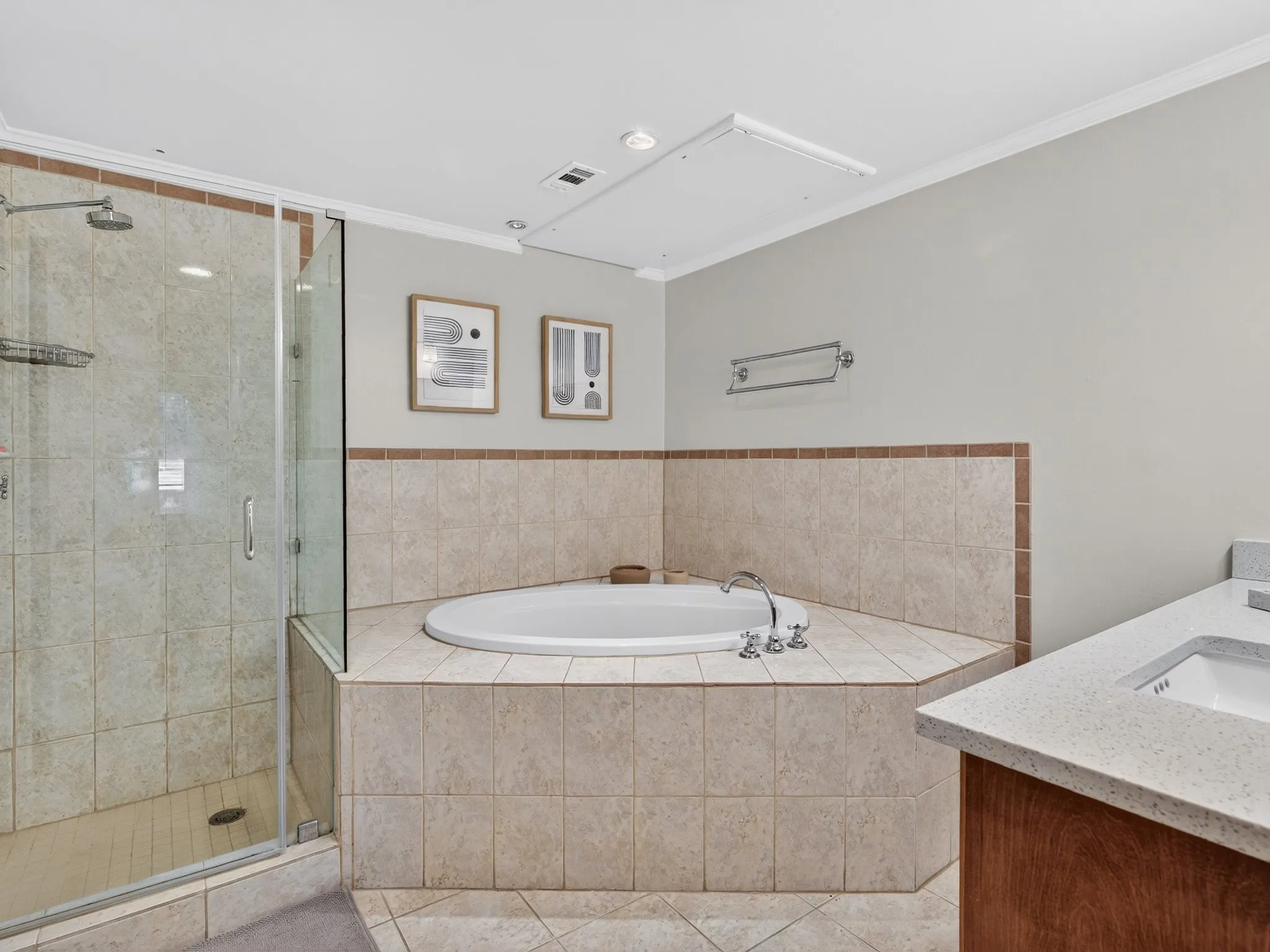 Walk-in shower with clear glass enclosure, corner soaking tub with tiled surround, and dual vanity with integrated sinks and light-toned countertops