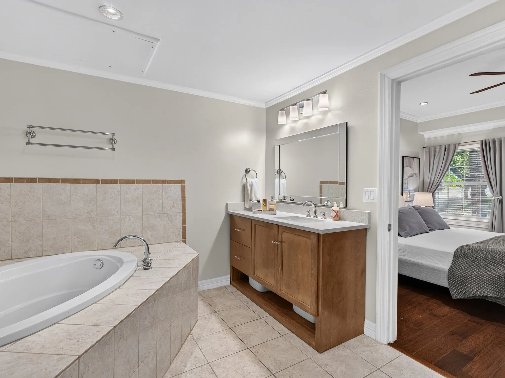 Spacious bathroom featuring a built-in soaking tub, a single vanity with stone-finish countertop, and tile flooring