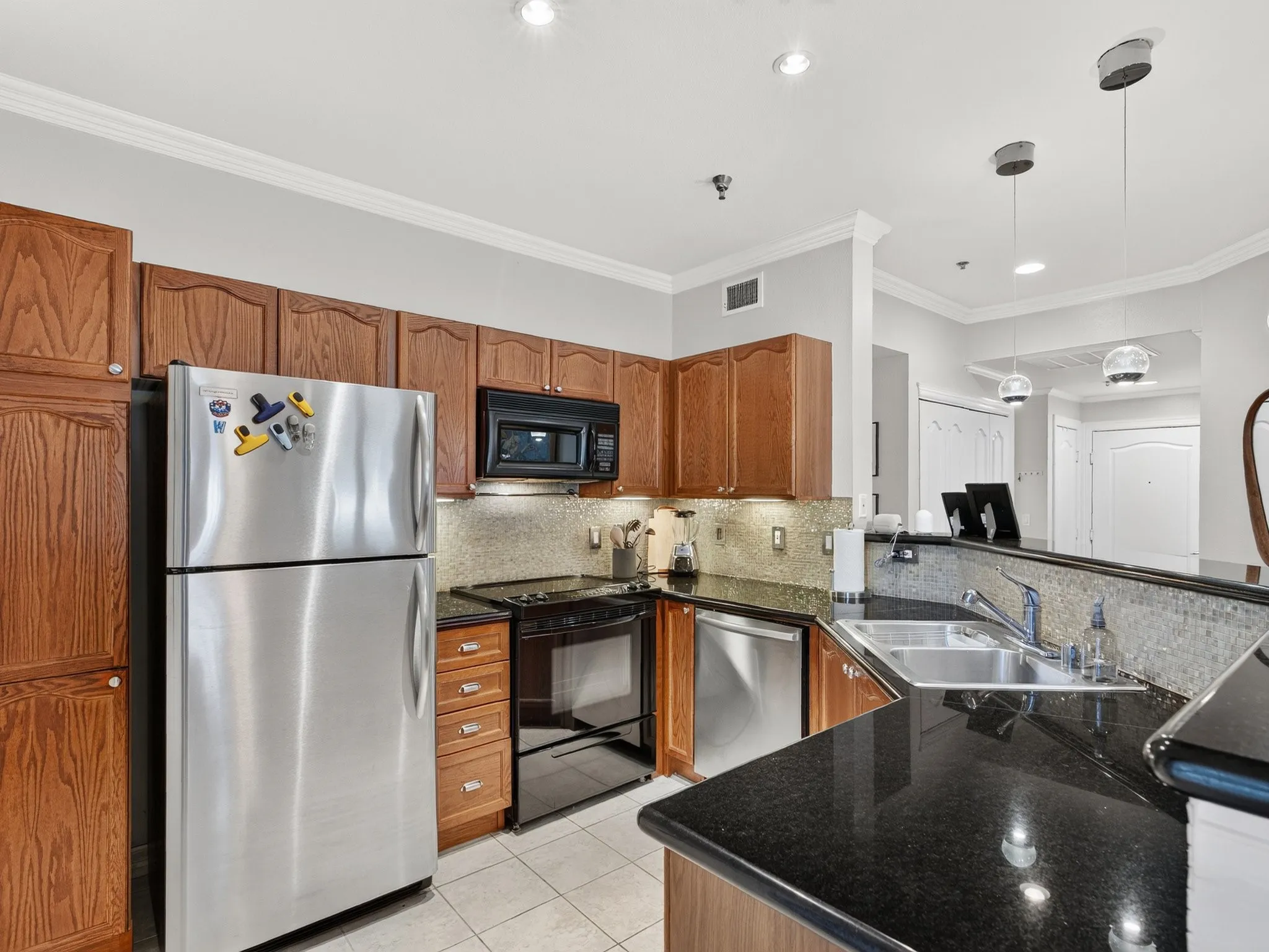 Kitchen featuring wood cabinetry, stainless steel appliances, dark countertops, and a tile backsplash