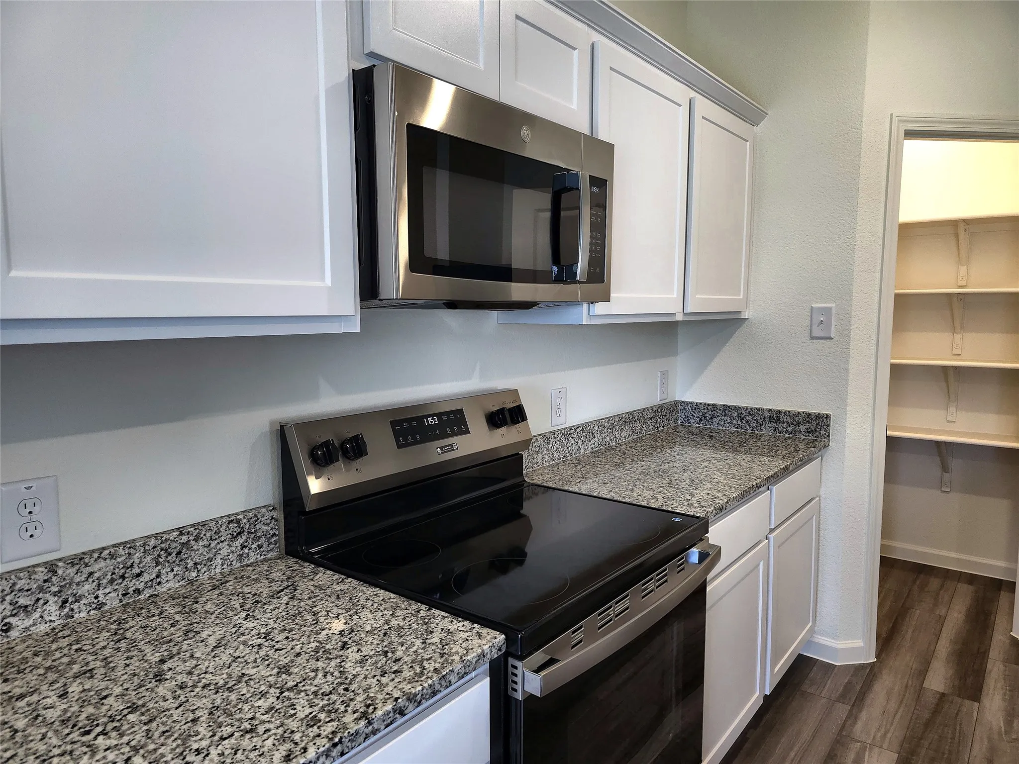 Stainless steel microwave, electric range, and granite-style countertops