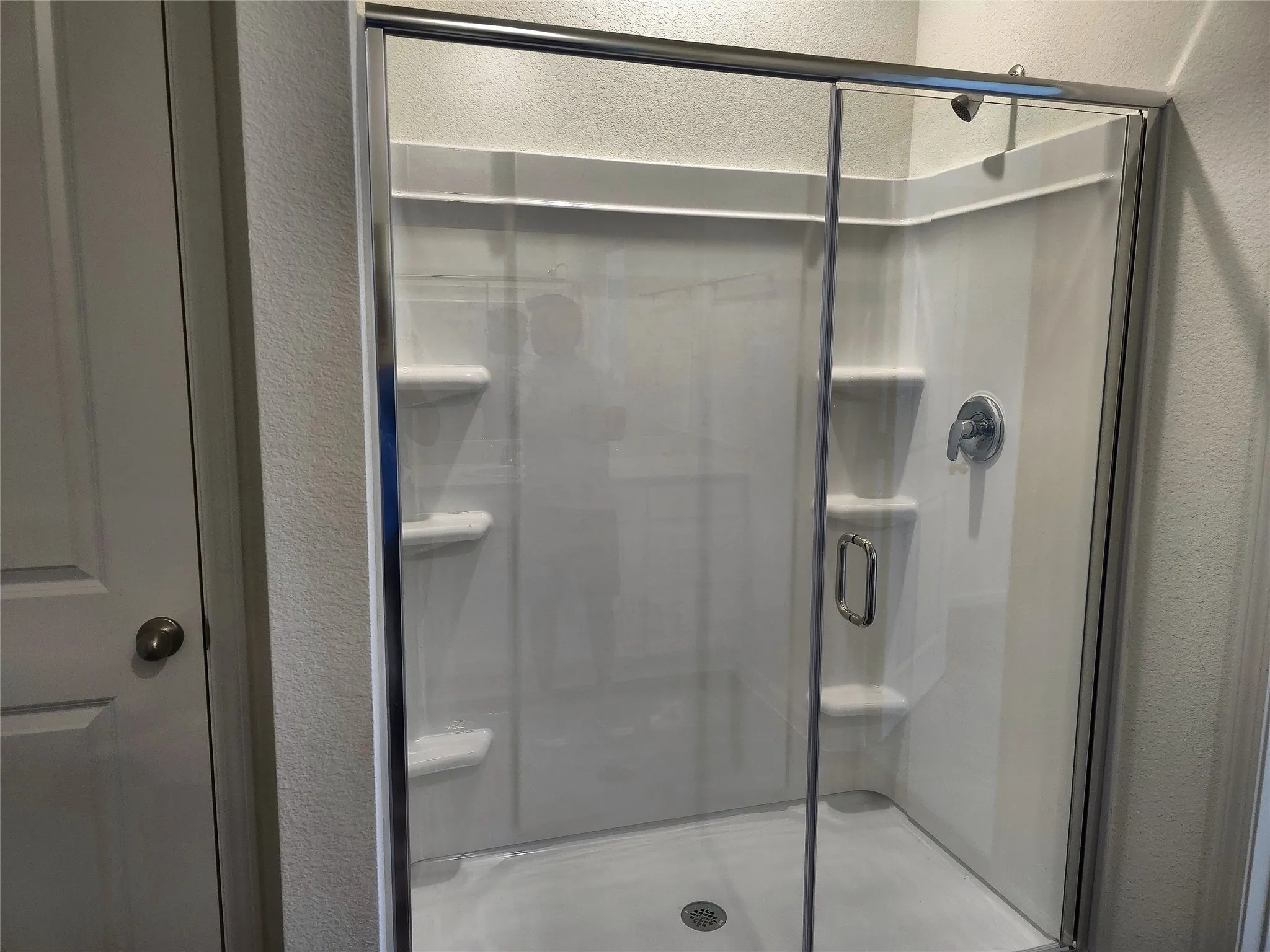 Walk-in shower with clear glass enclosure and integrated shelving