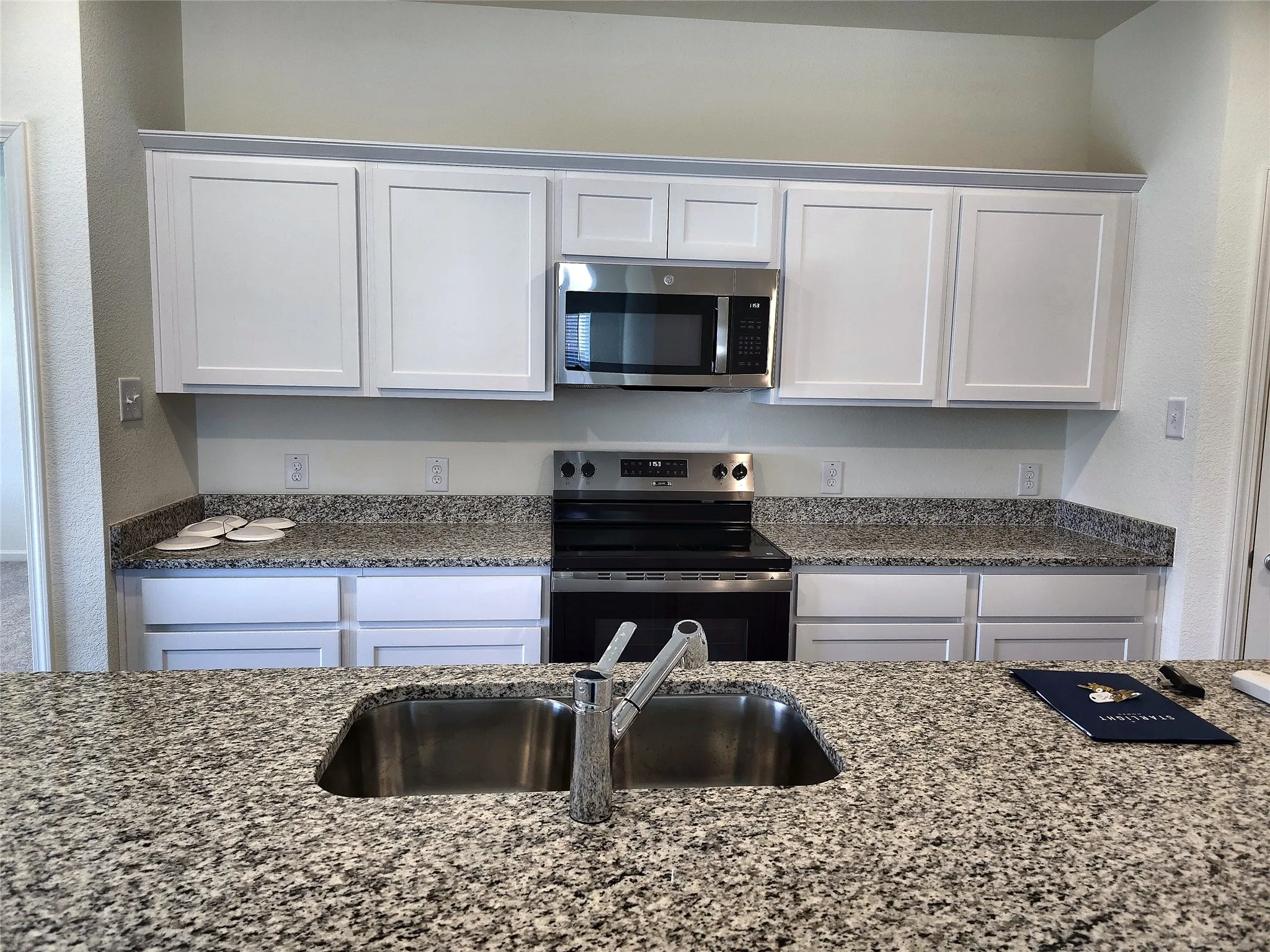 Kitchen featuring a stainless steel sink, stainless steel appliances, granite countertops, and white shaker-style cabinetry