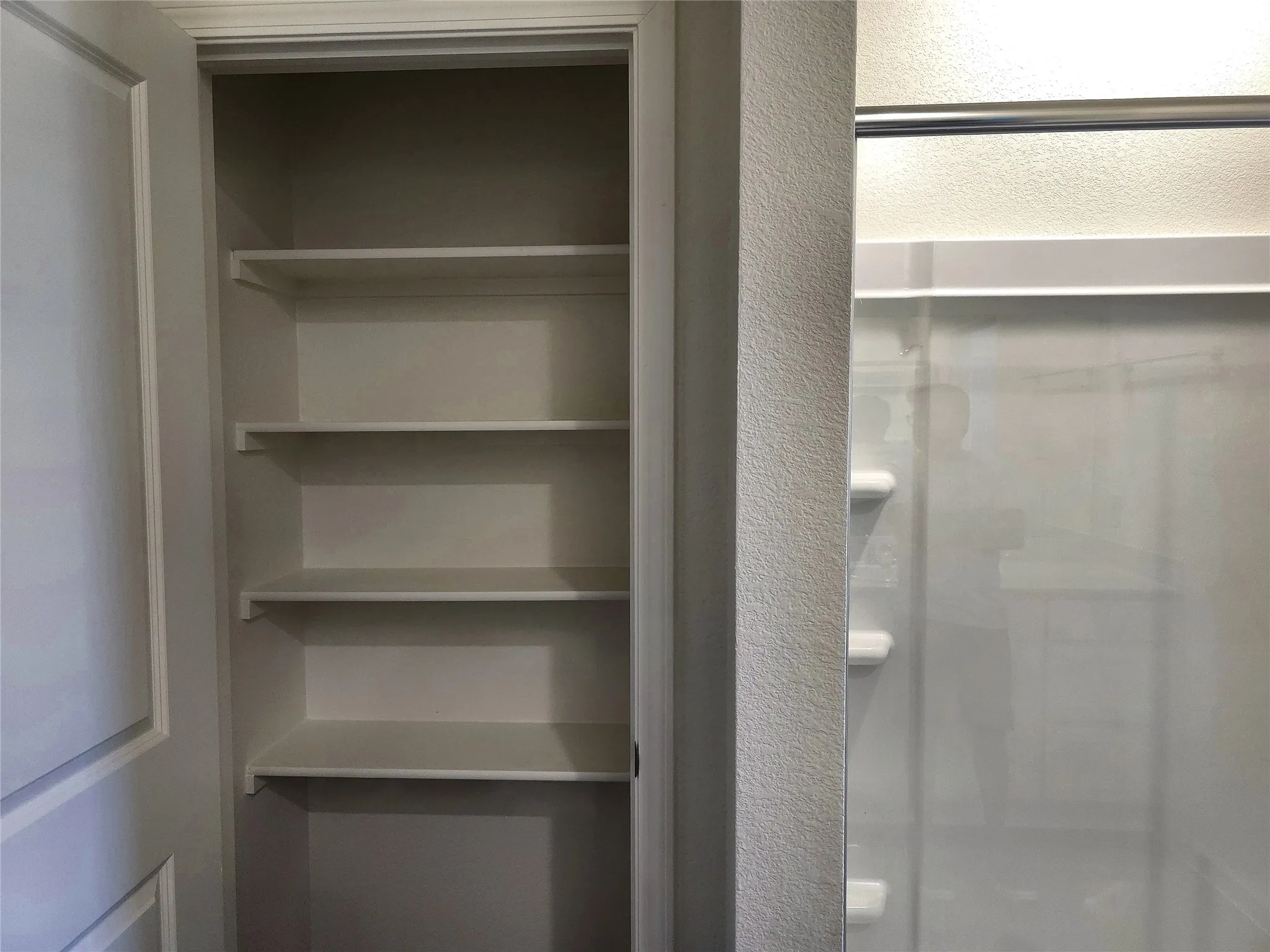 Built-in shelving with multiple levels, white finishes, and a textured wall