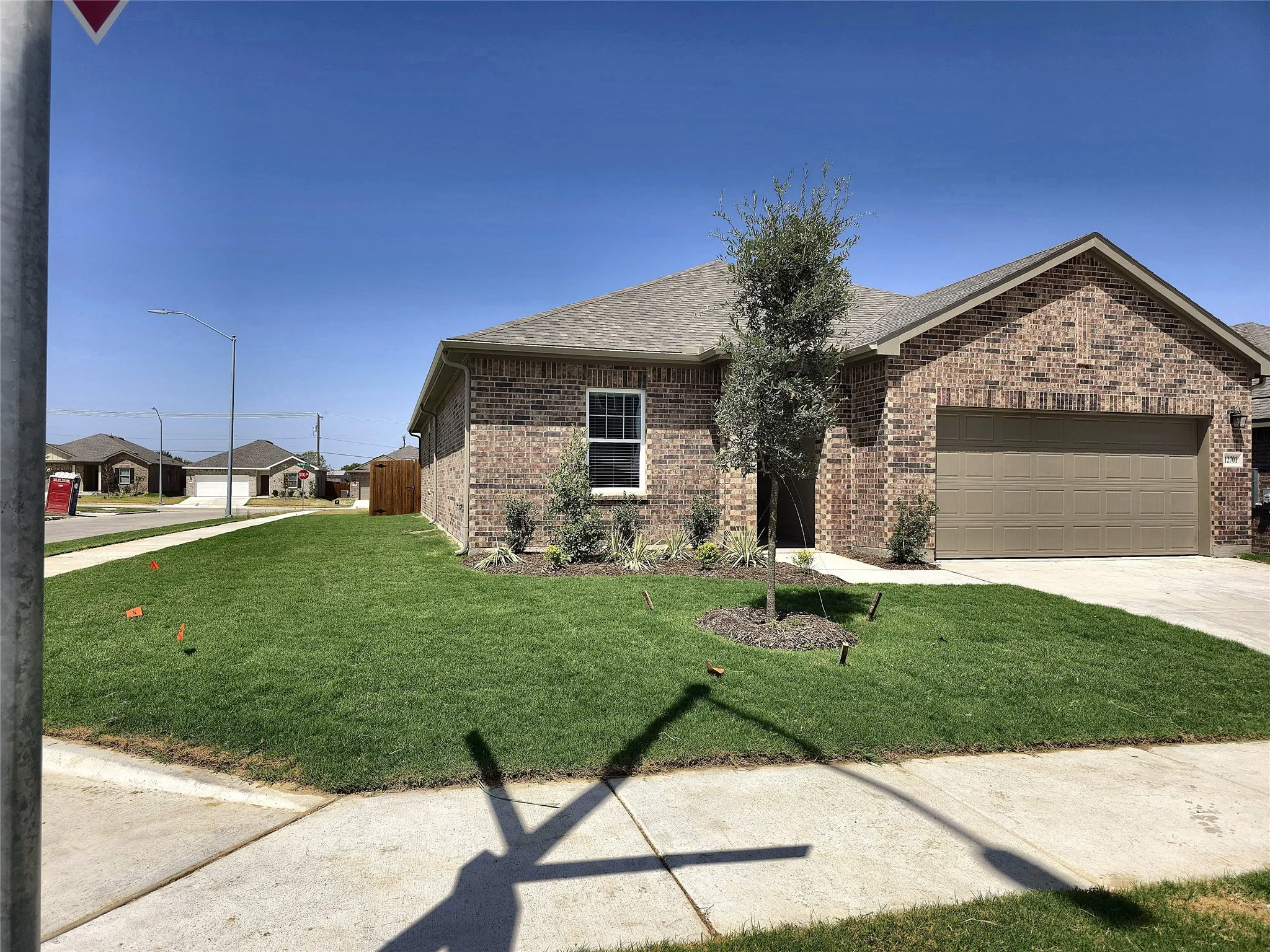 Brick exterior, gabled roofline, attached garage, concrete driveway, and front yard landscaping