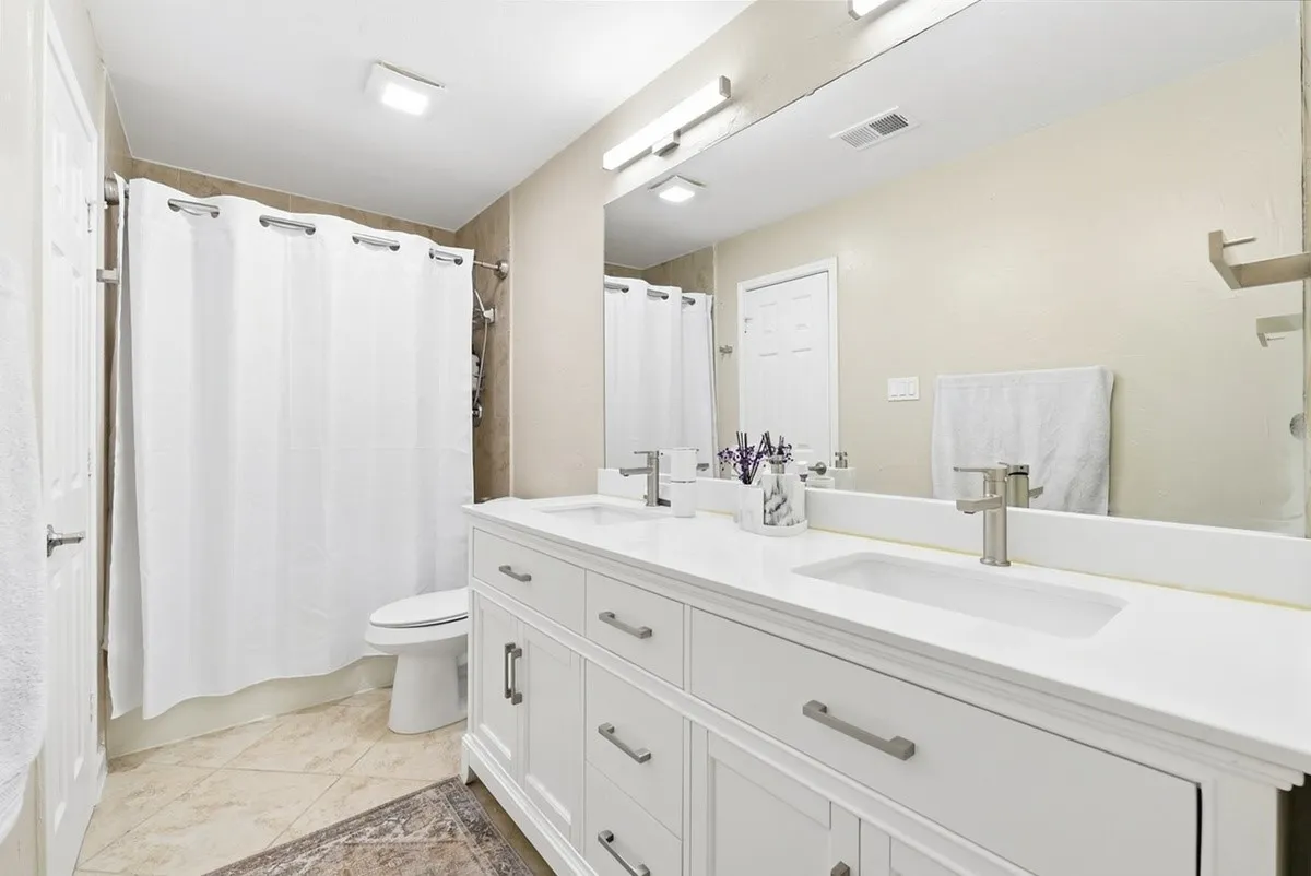 Dual vanity with white cabinetry, integrated sinks, and brushed nickel fixtures