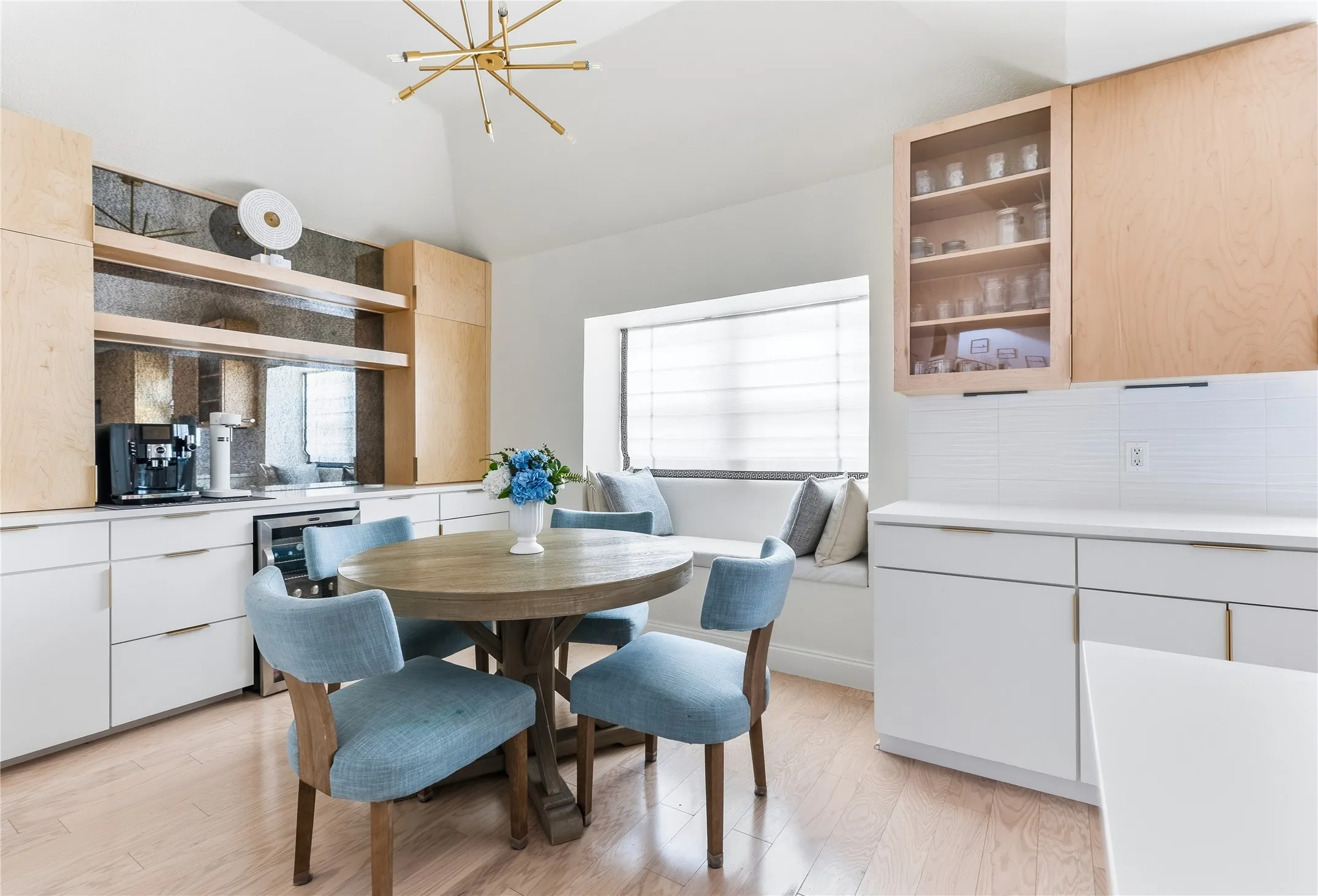 Vaulted ceiling with a contemporary light fixture, wood-finish flooring, built-in window seating, and a built-in beverage refrigerator
