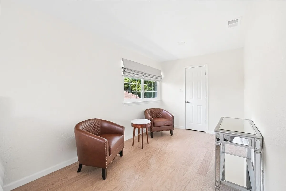 Light wood-finish flooring, white walls, recessed ceiling lighting, and a white paneled door