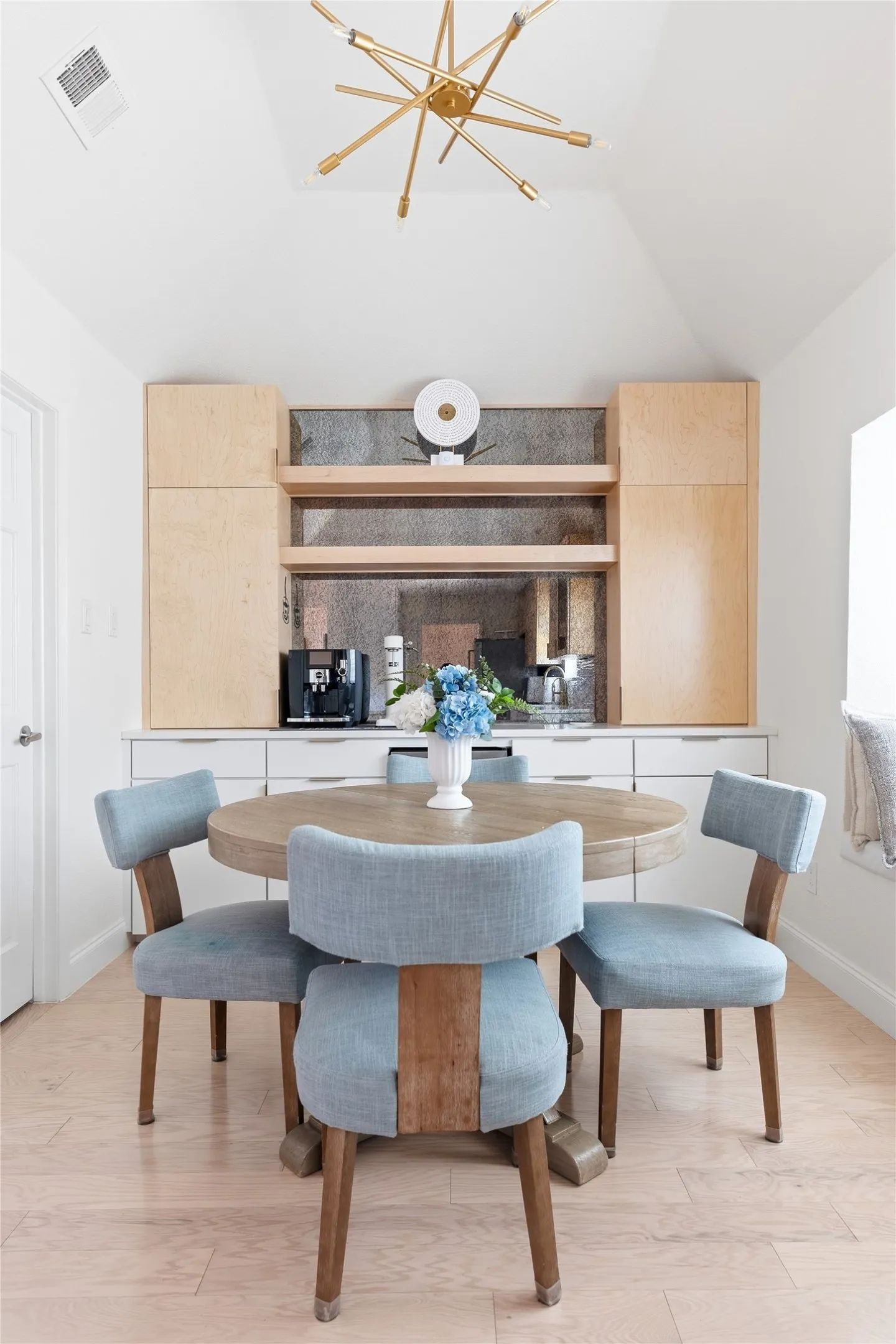 Vaulted ceiling with a contemporary brass chandelier, light wood-finish flooring, built-in cabinetry, and integrated shelving