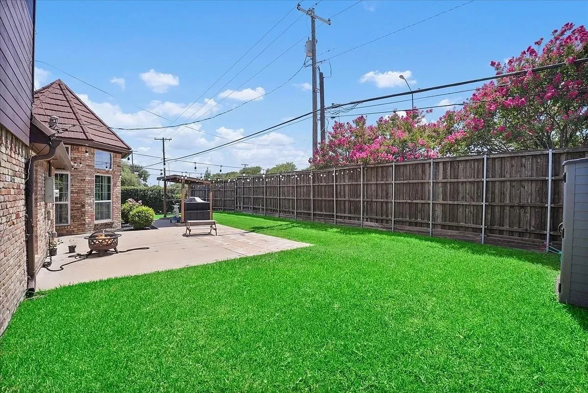 Expansive lawn area, brick exterior, concrete patio, privacy fencing, and flowering trees