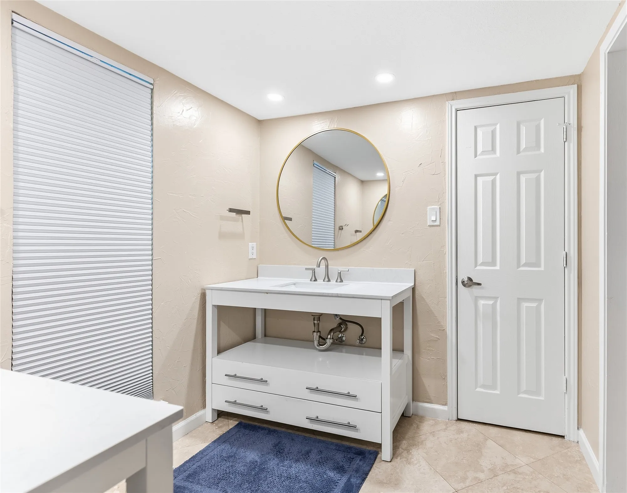 Vanity with integrated sink, gold-framed mirror, recessed lighting, and panel door
