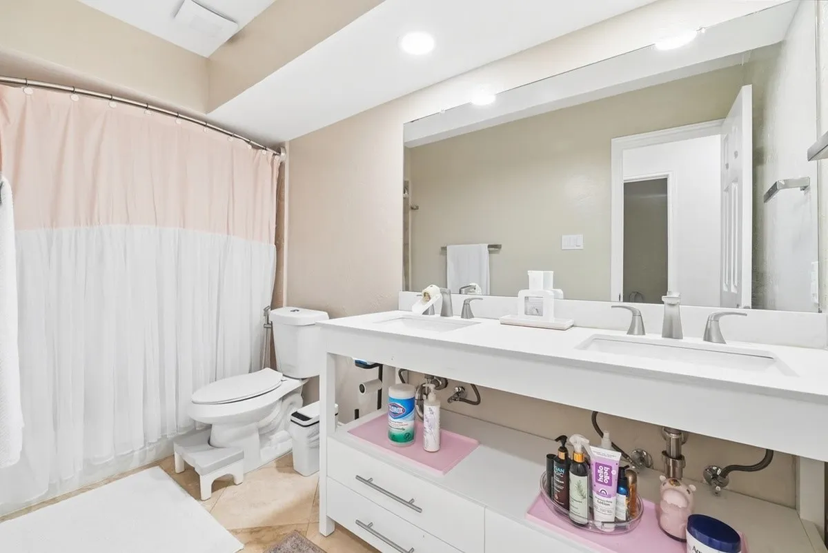 Dual vanity with integrated sinks, white cabinetry, and a large​​‌​​​​‌​​‌‌​‌‌​​​‌‌​‌​‌​‌​​​‌​​ mirror