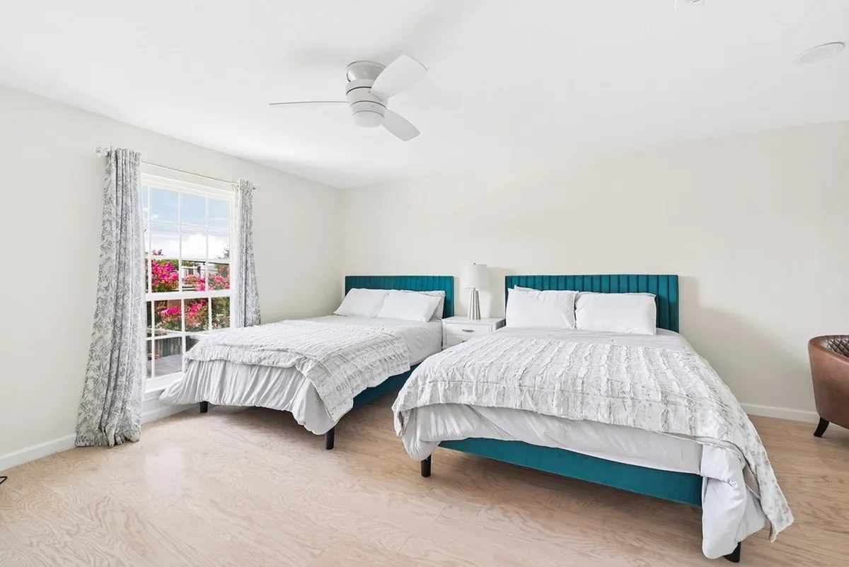 Bright room with overhead ceiling fan, window with exterior scenery, and wood-finish flooring