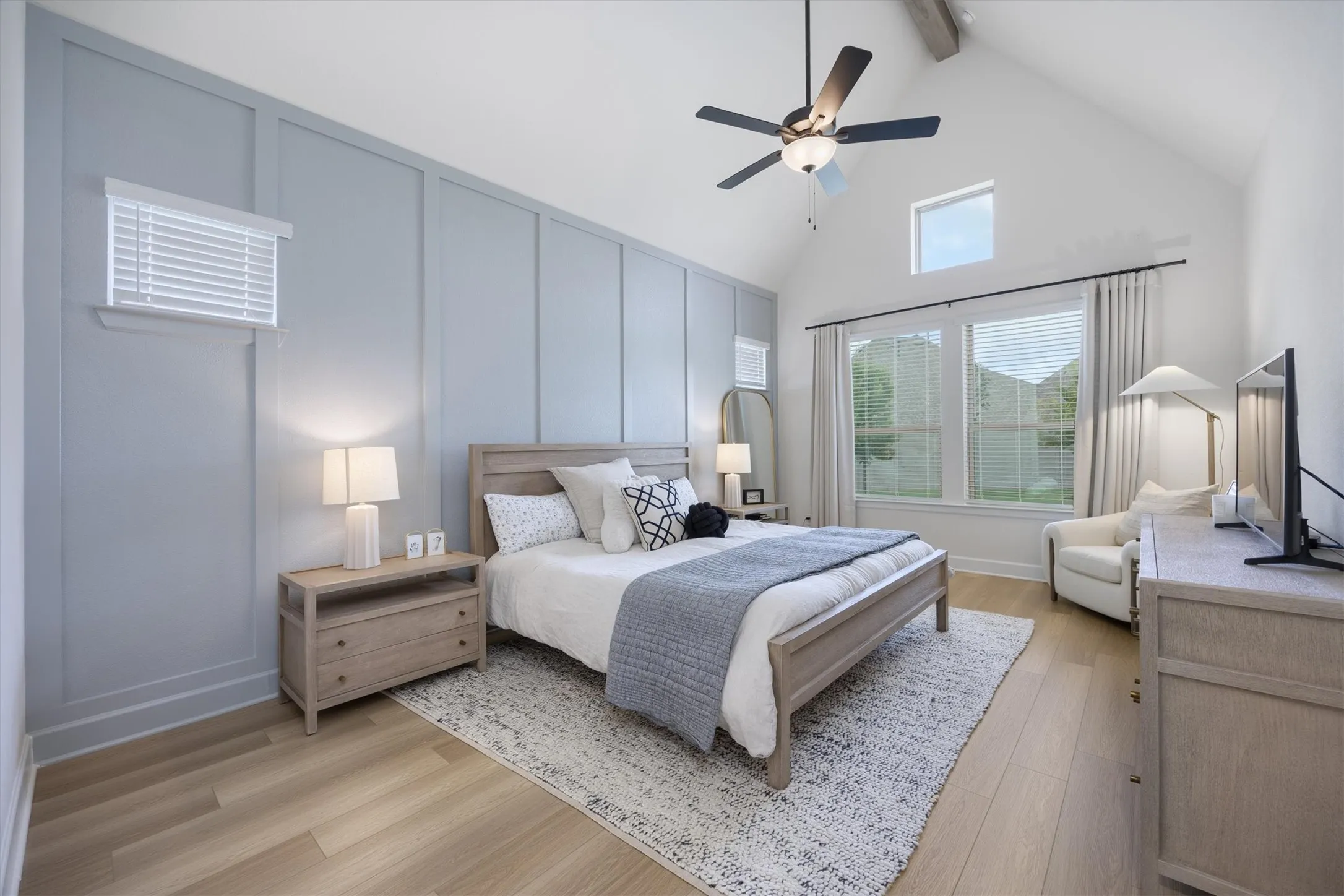 The master suite offers a board and batten designer accent wall and high ceilings with another view to the backyard.