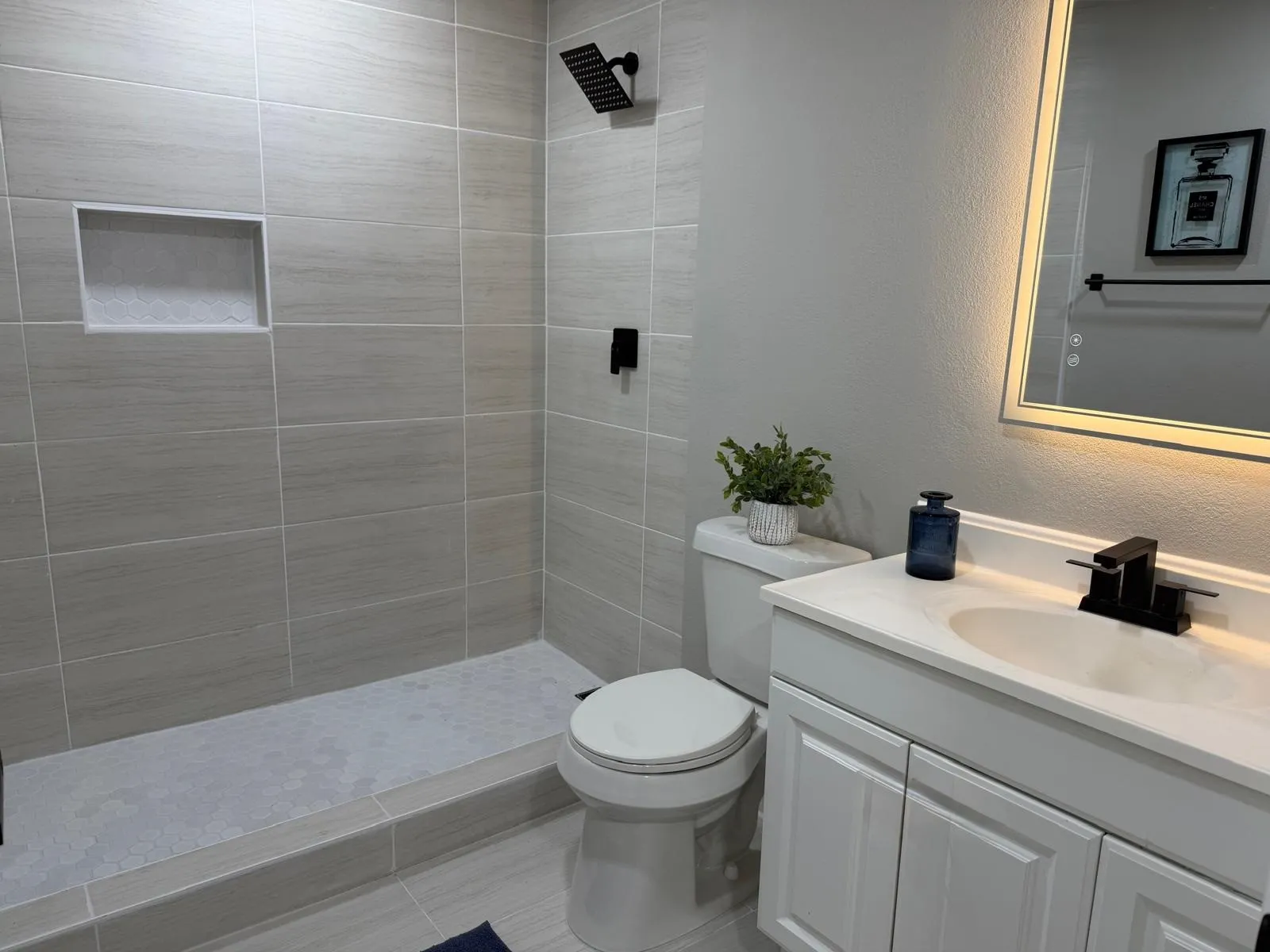 Tiled shower with a built-in niche, black rainfall showerhead, and black fixtures