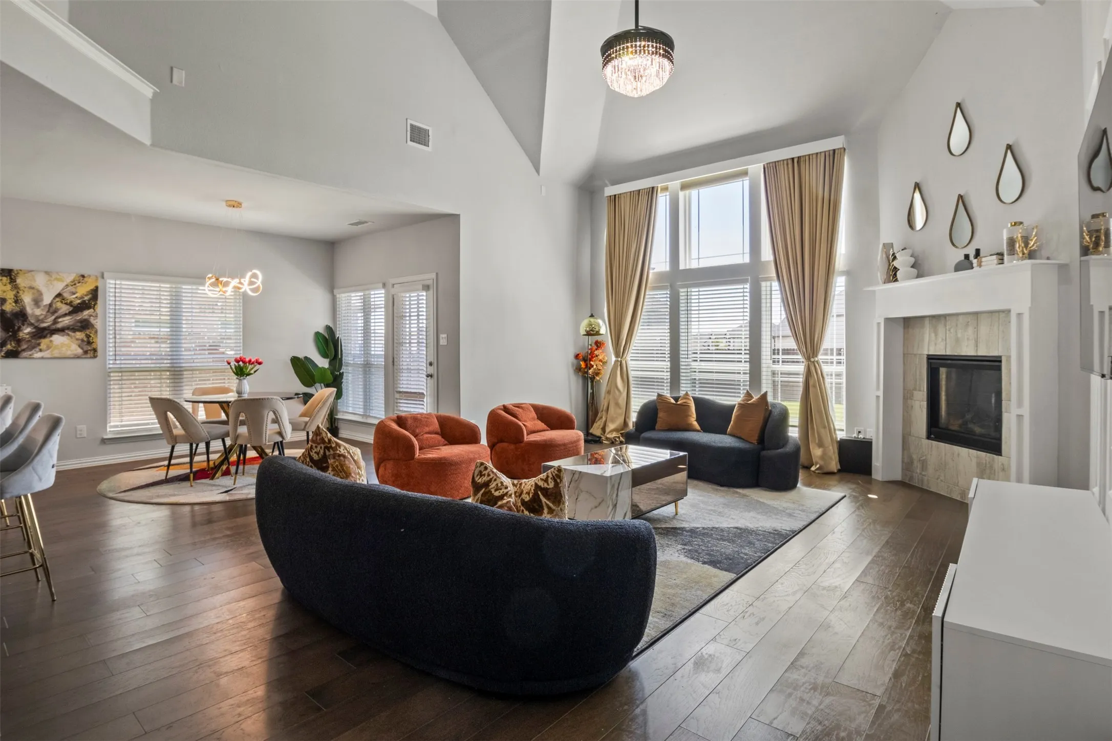 Vaulted ceiling, wood-finish flooring, fireplace with tile surround, large windows, and built-in shelving
