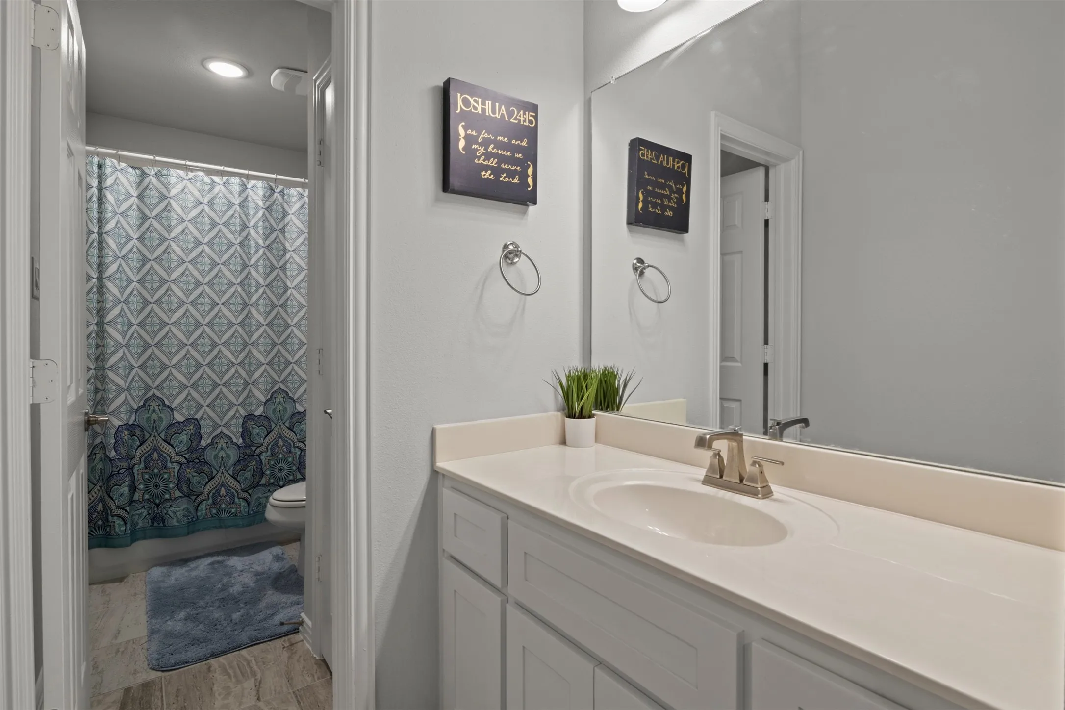 White vanity with an integrated sink, brushed nickel faucet, and a large wall-mounted mirror