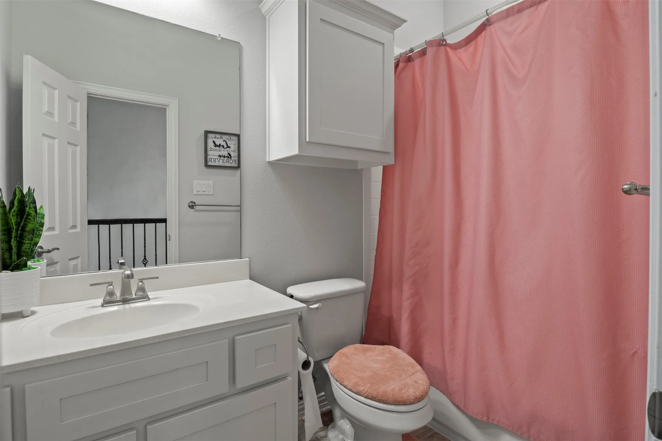 Bathroom featuring a single vanity with an undermount sink, a toilet, and a shower with a shower curtain rod