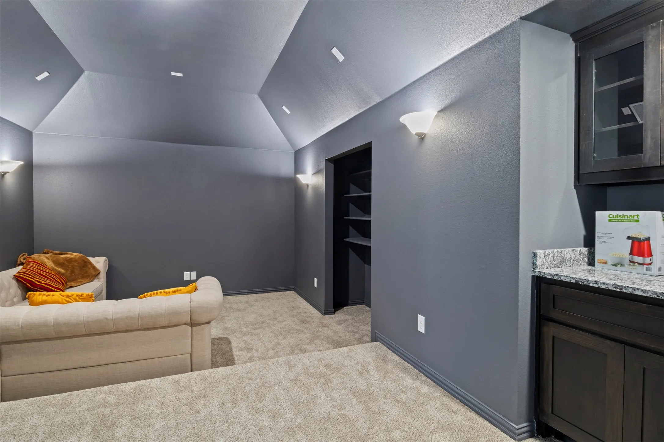 Vaulted ceiling with recessed lighting, built-in shelving, sconce lighting, built-in cabinetry, and a stone-finish countertop