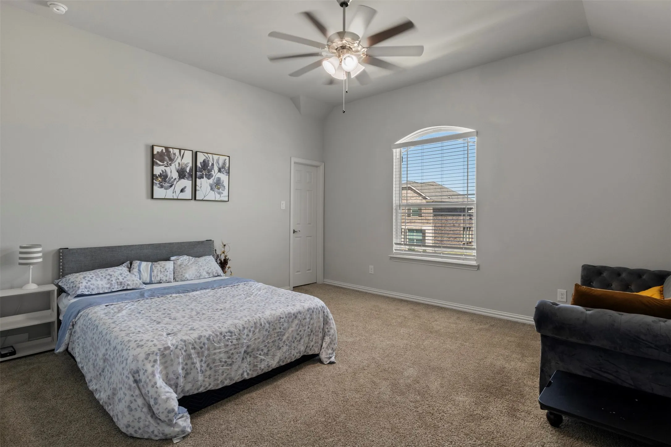 Vaulted ceiling, ceiling fan, arched window, wall-to-wall carpeting, and a built-in door
