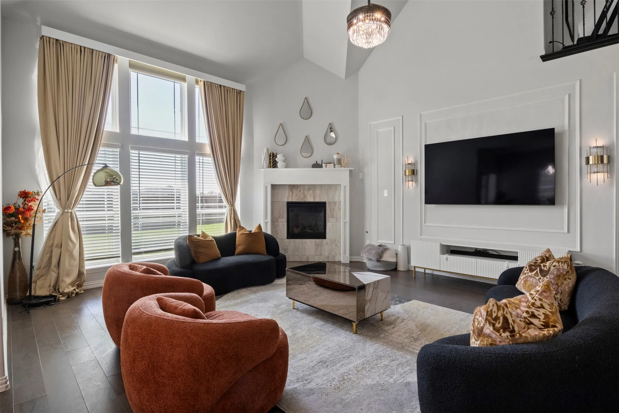 Sophisticated living room showcasing soaring ceilings, a gas fireplace with decorative surround, and wood-finish flooring throughout