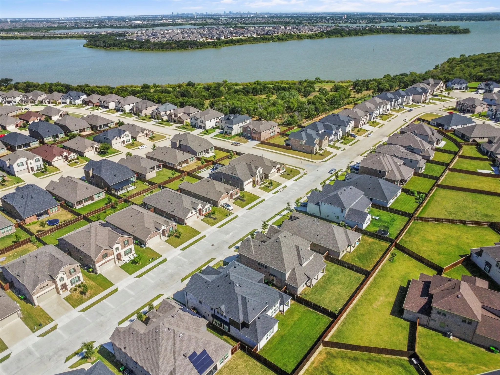 Residential community with varied architectural styles, individual fenced yards, paved streets, and a prominent water feature