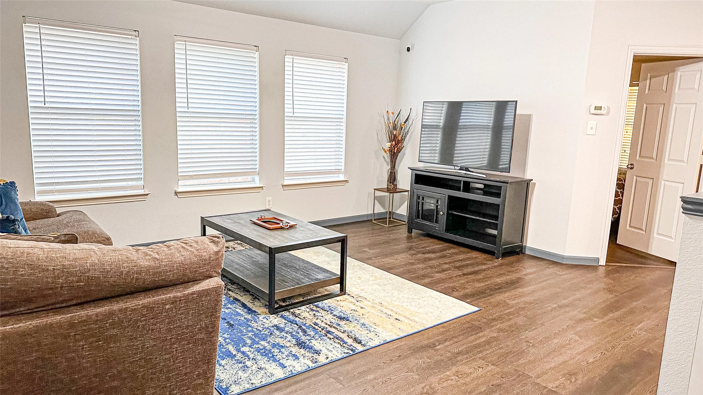 Living room with wood finished floors, lofted ceiling, and baseboards