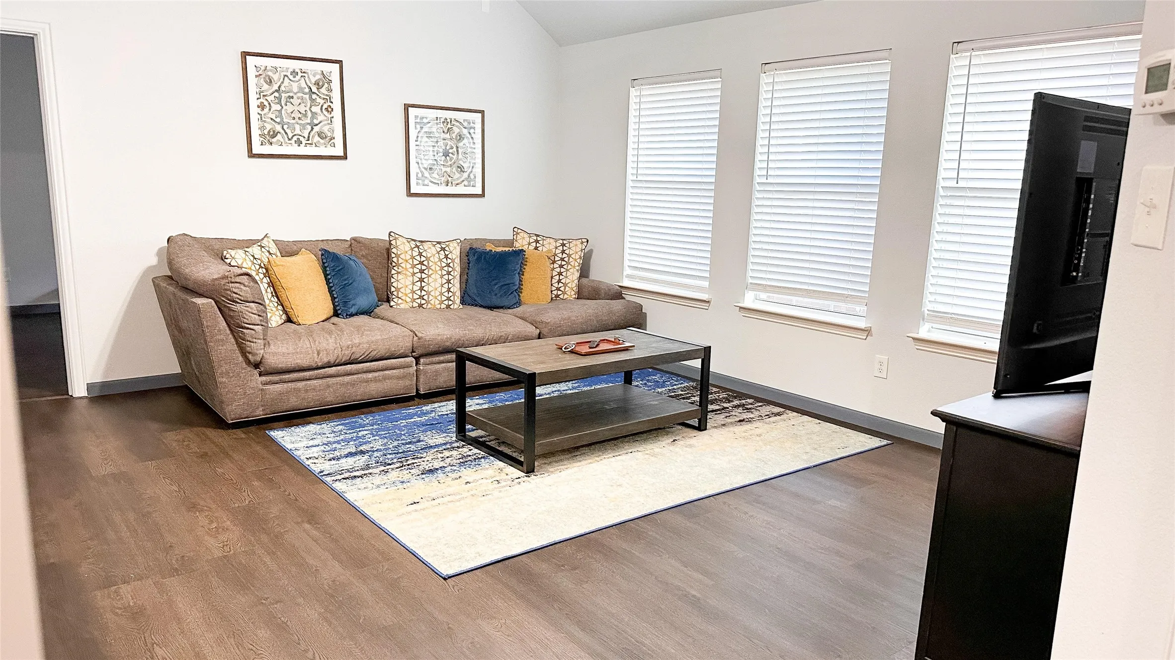 Living room featuring wood finished floors, baseboards, and lofted ceiling