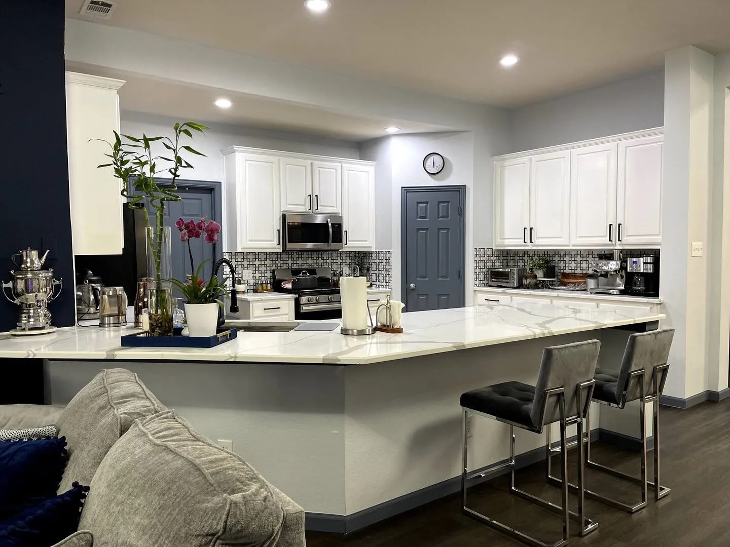 Kitchen with a kitchen breakfast bar, light stone counters, dark wood-style floors, white cabinetry, and stainless steel appliances
