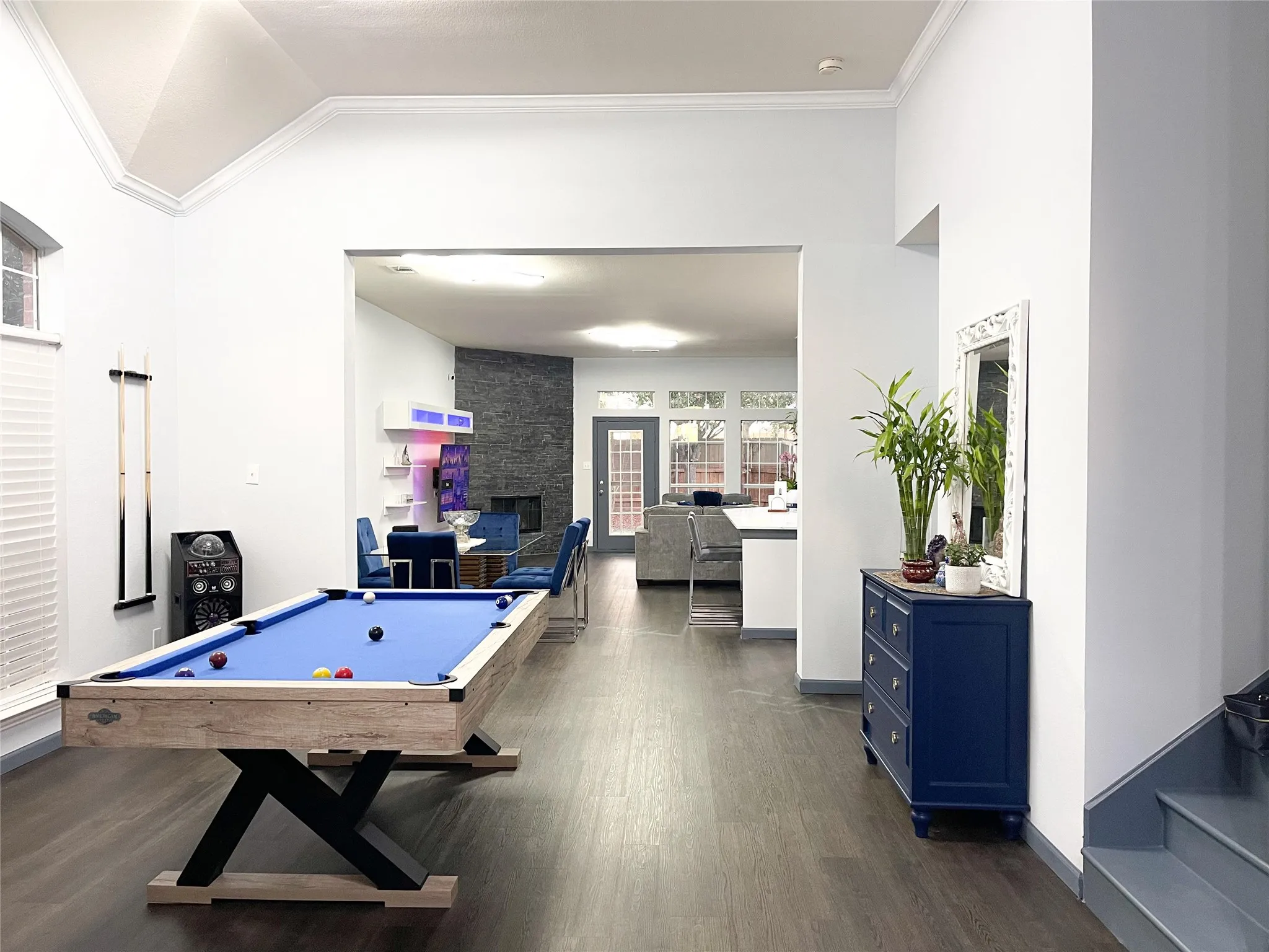 Recreation room with dark wood-style flooring, a stone fireplace, crown molding, lofted ceiling, and billiards table