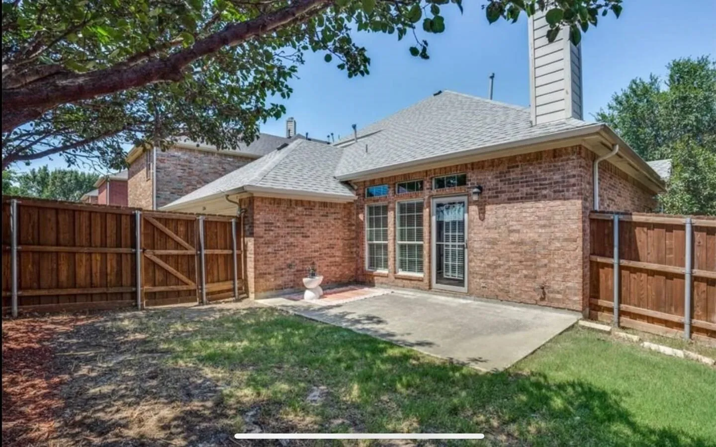 Rear view of house featuring fence, a patio, brick siding, a gate, and roof with shingles