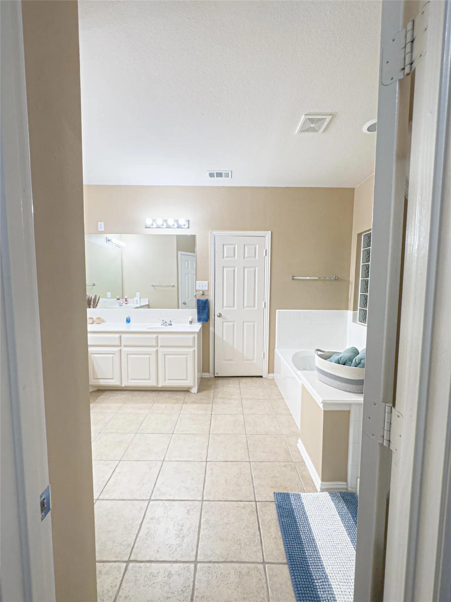 Bathroom featuring tile patterned floors, a garden tub, double vanity, and a textured ceiling