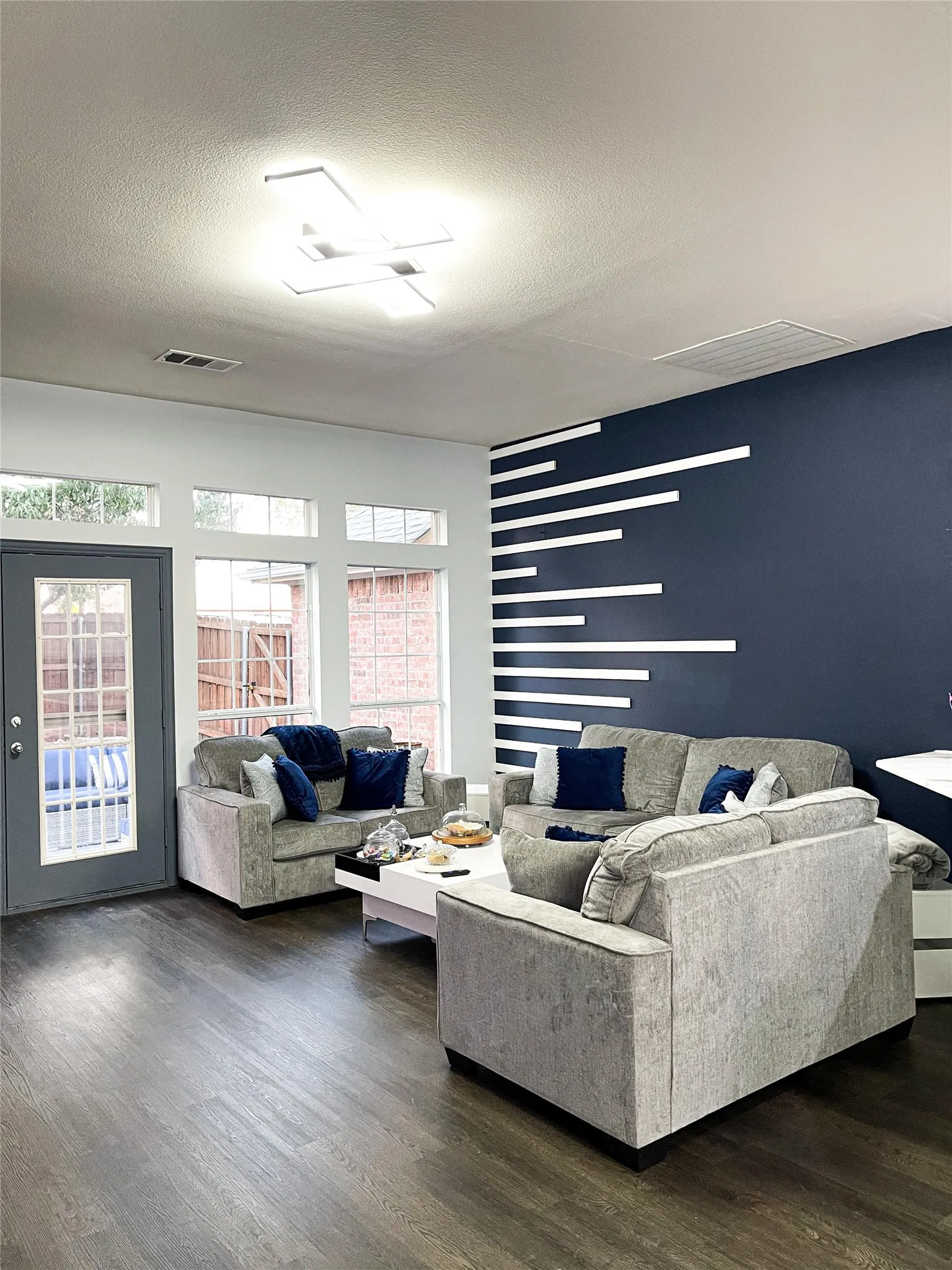 Living room featuring dark wood-style floors, healthy amount of natural light, and a textured ceiling