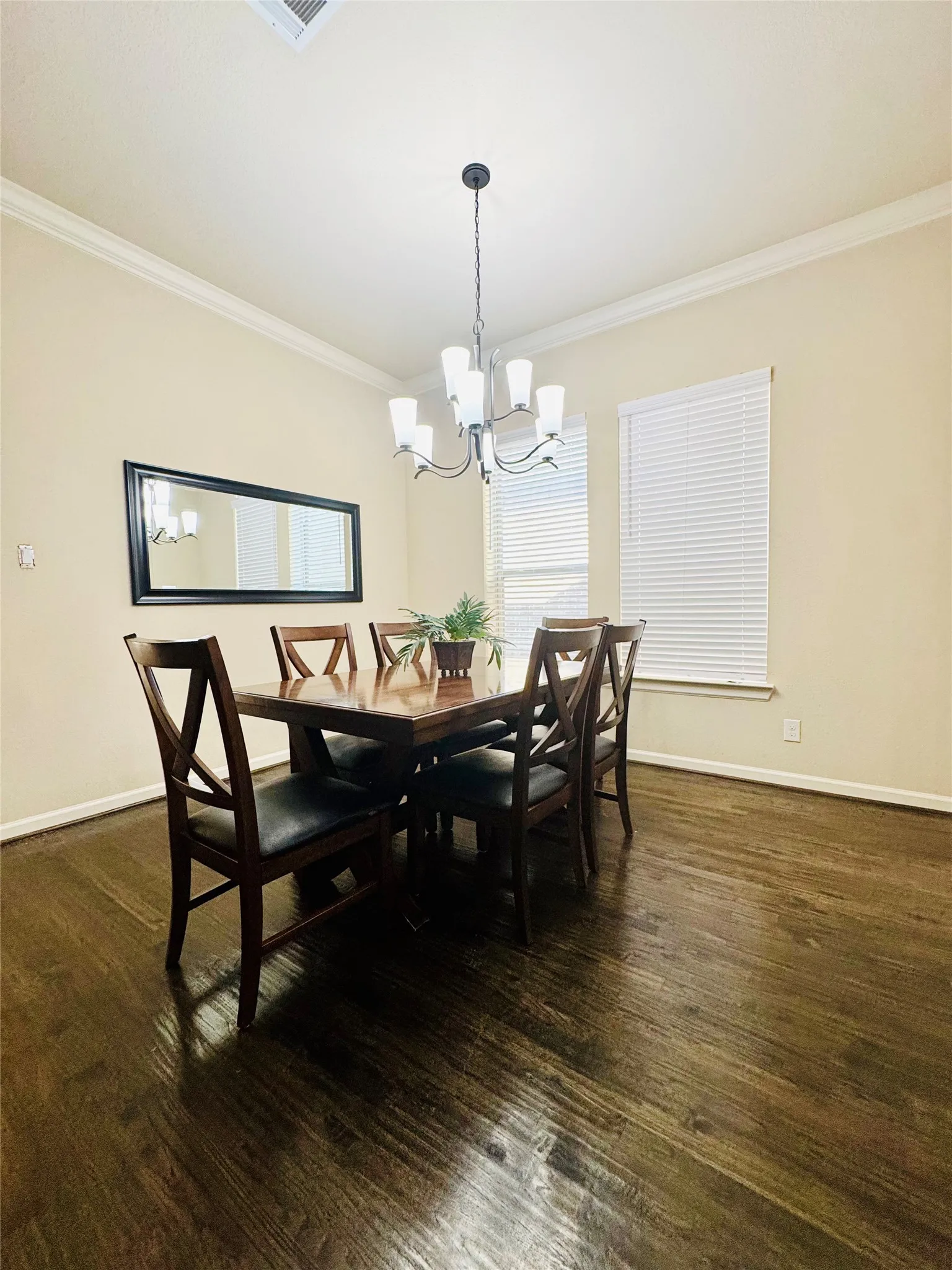 Dark wood-finish flooring, crown molding, and a multi-light chandelier