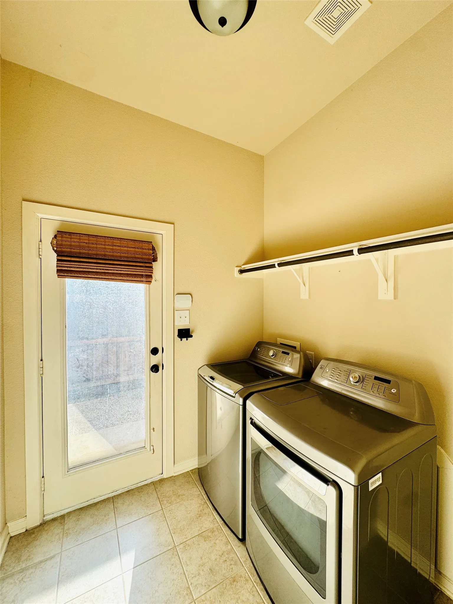 Laundry area with tile flooring, a built-in shelving unit, and a glass-paneled exterior door