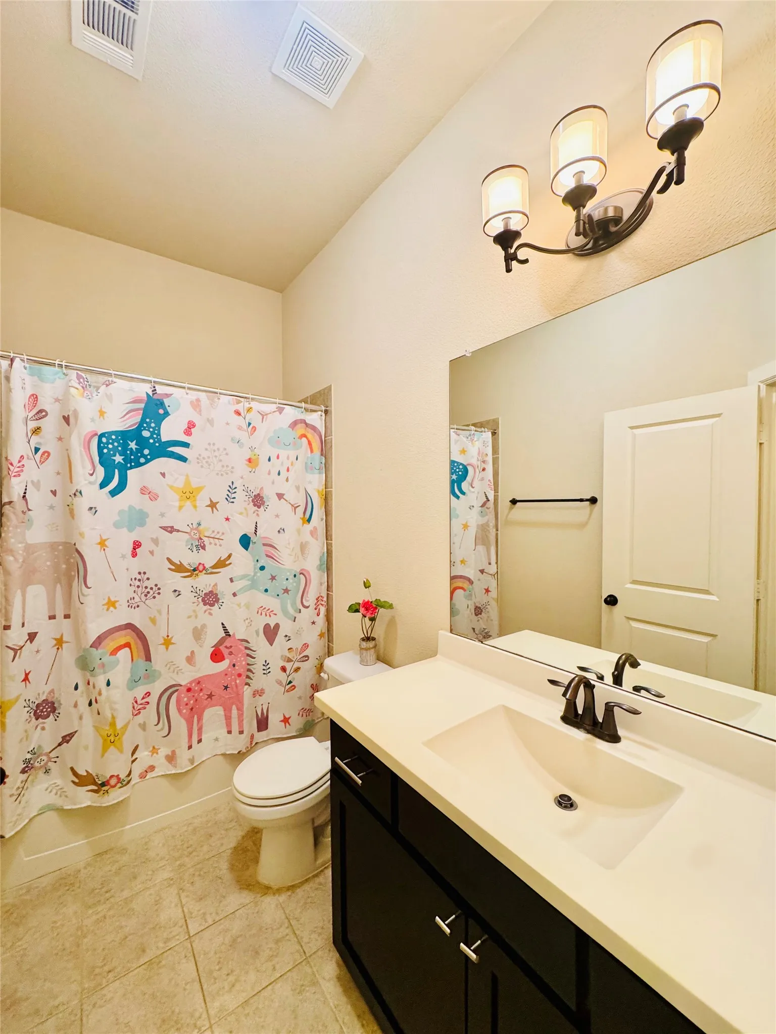 Bathroom featuring a single vanity with dark cabinetry, integrated sink, and light-toned countertop