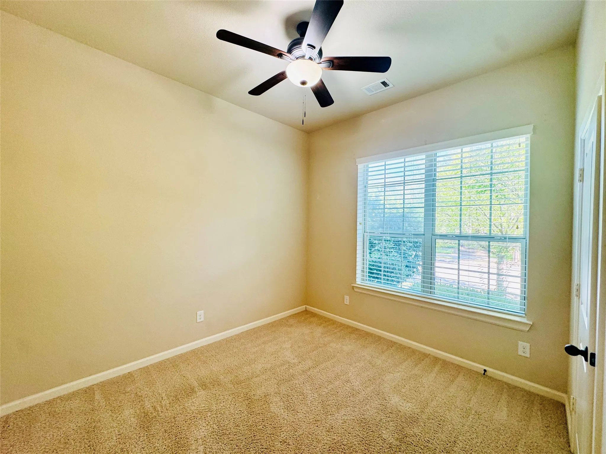 Carpeted room with a ceiling fan, a window with blinds, and neutral wall tones