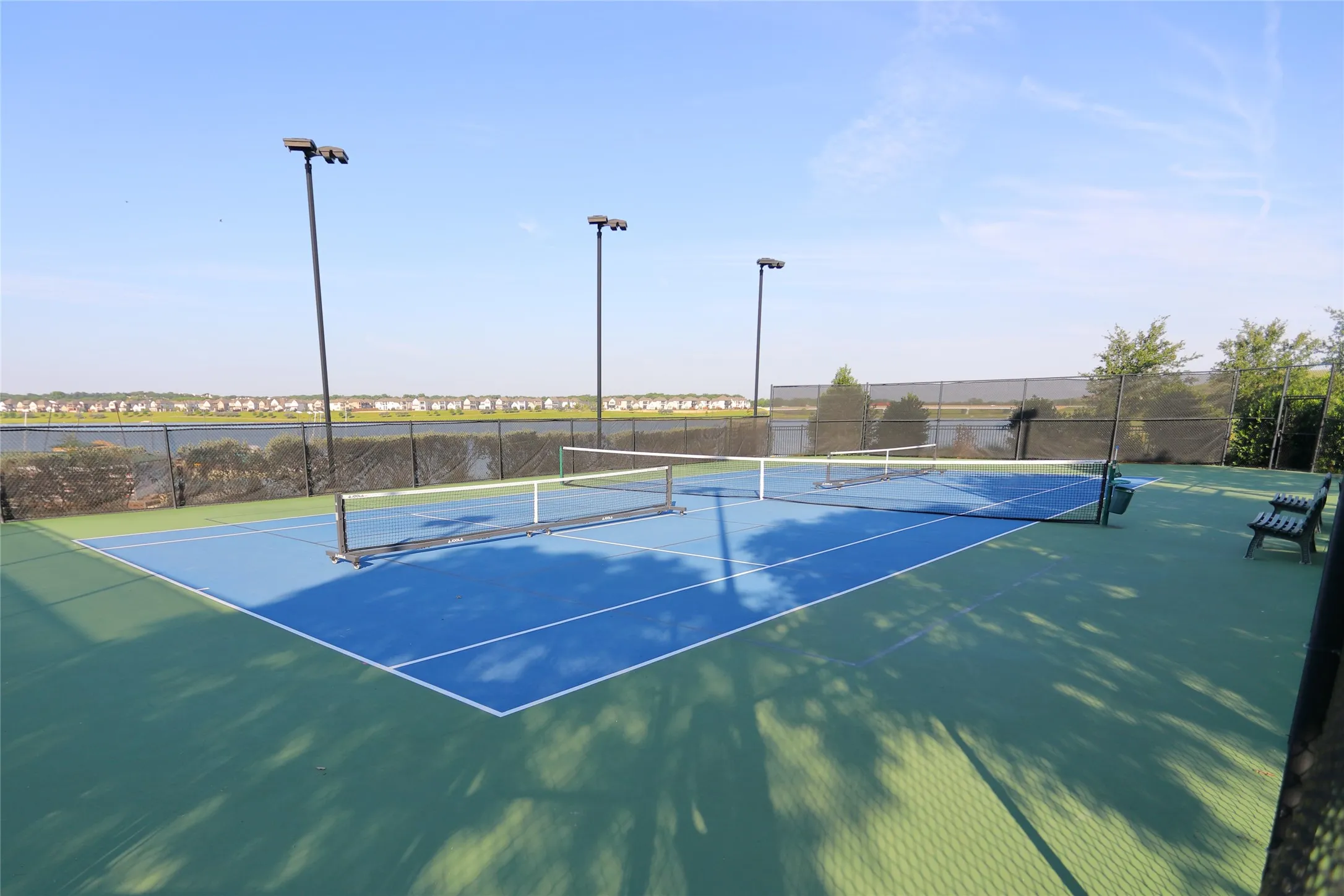 Two outdoor tennis courts featuring blue and green hard surfaces