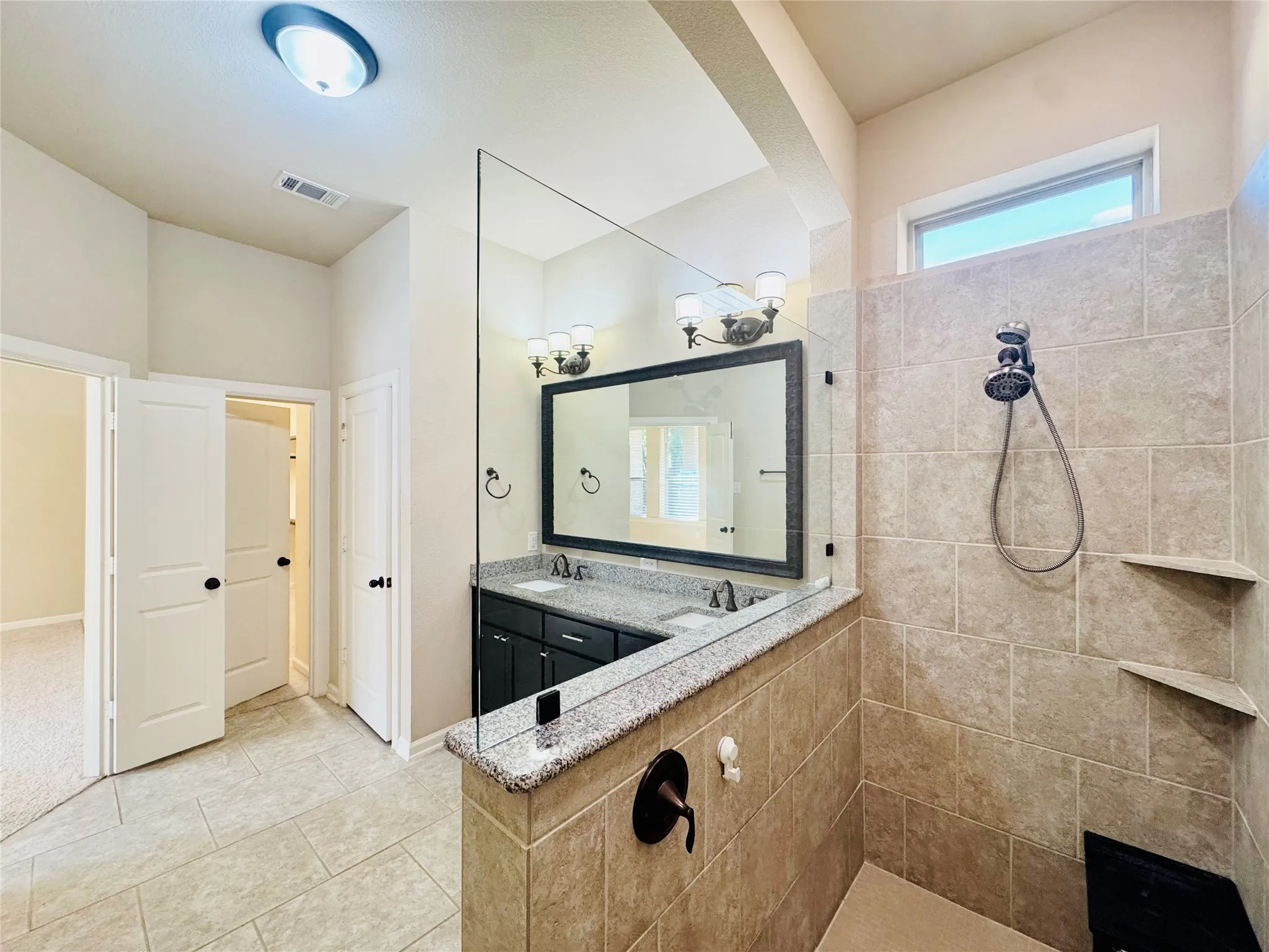 Dual vanity with dark cabinetry, stone countertop, and individual vessel sinks