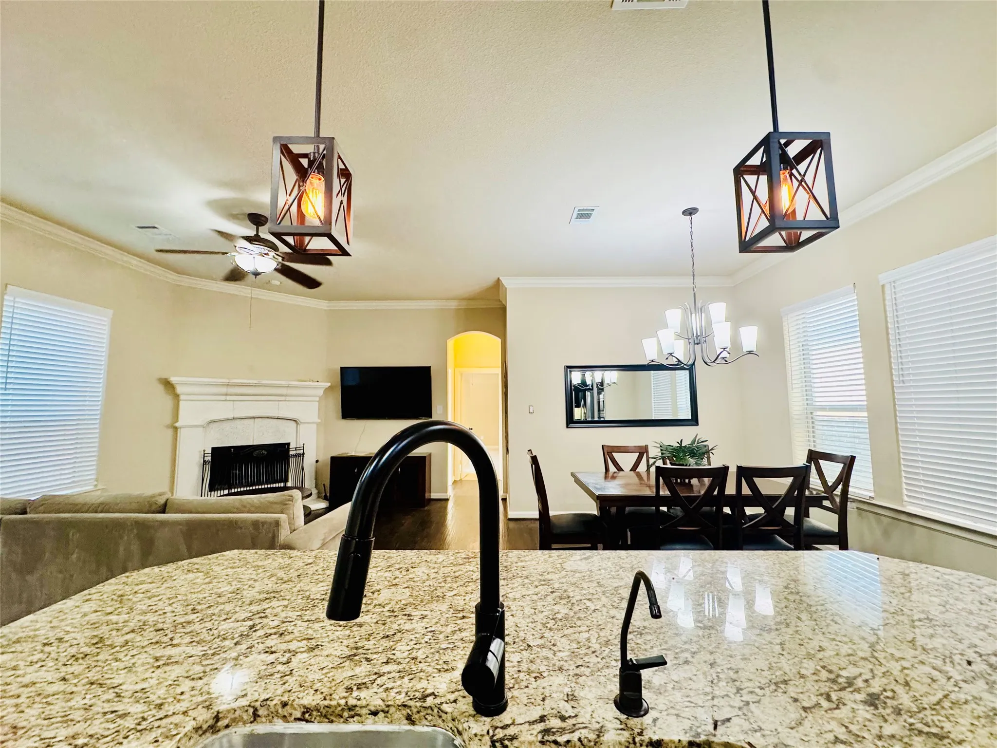 Open-concept living space with a fireplace, vaulted ceilings, and crown molding