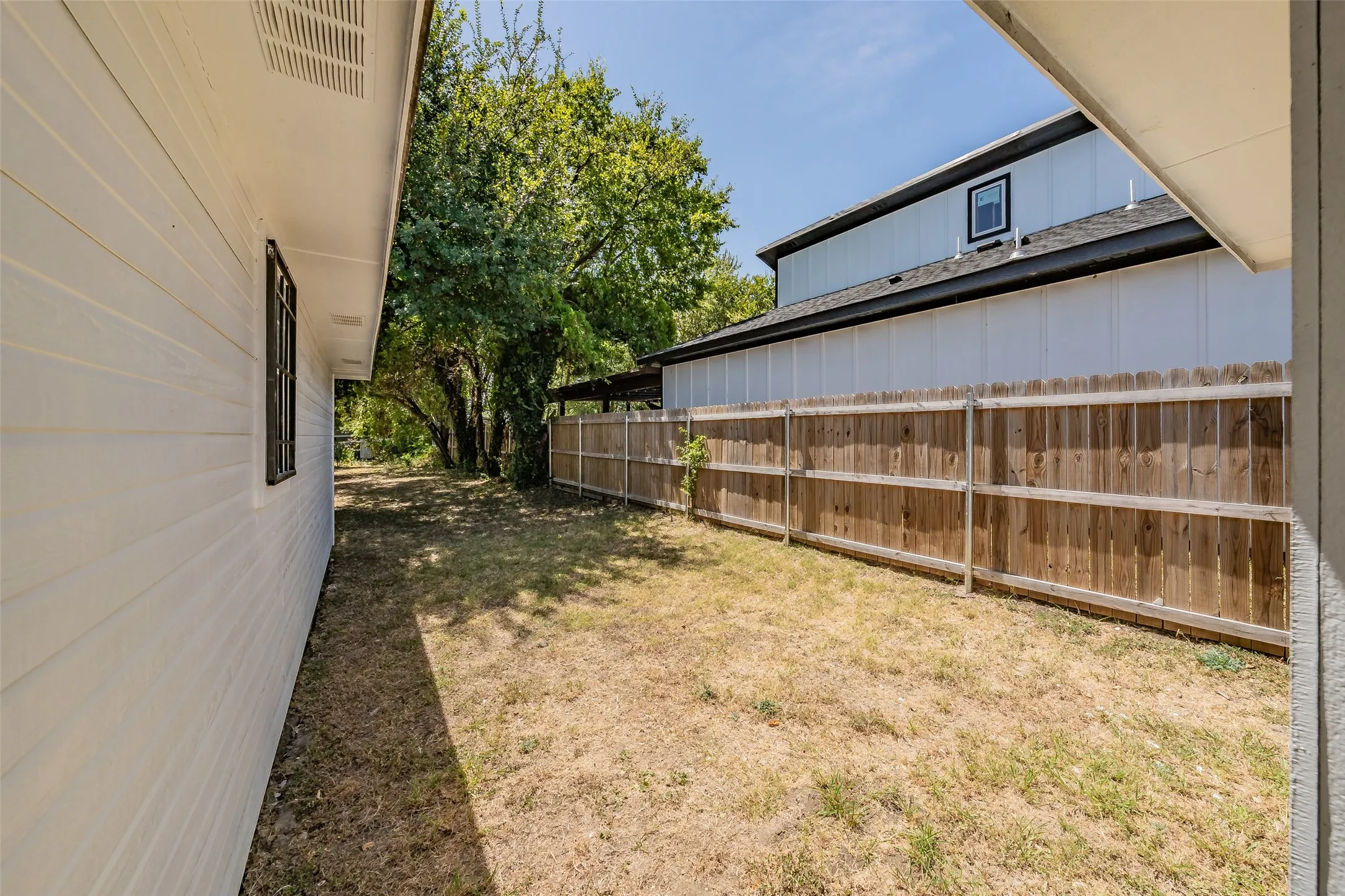 Side yard with a wood privacy fence and mature trees