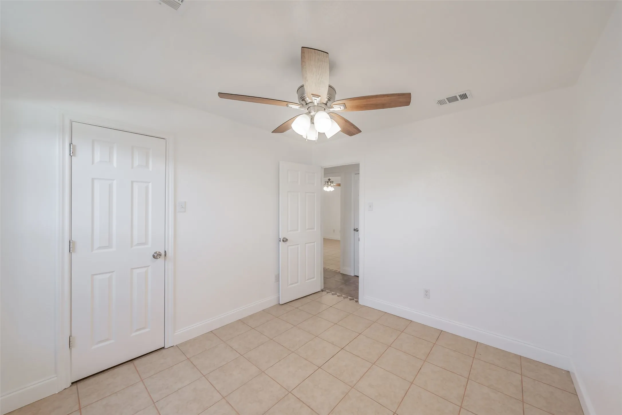 Recessed lighting, ceiling fan with wood-finish blades, tile flooring, six-panel doors, and white painted walls