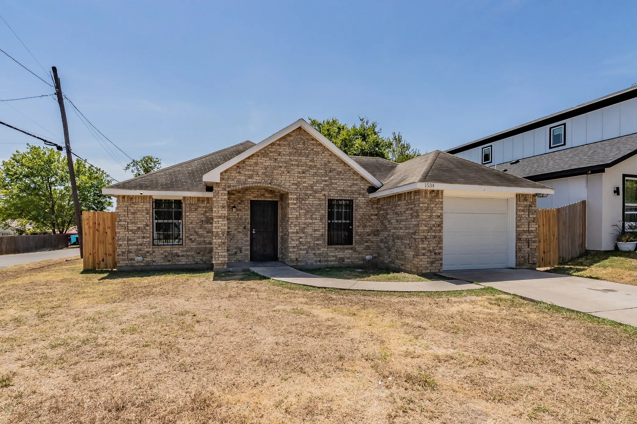 Brick facade with an arched entry, attached single-car garage, and a concrete driveway