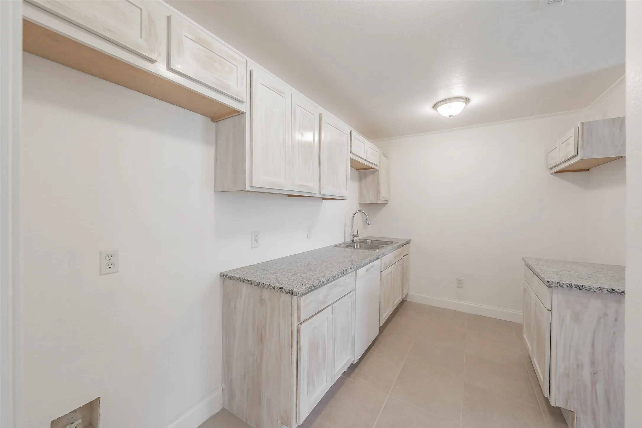 Kitchen featuring light wood-finish cabinetry, light-toned countertops, and a stainless steel sink with a chrome faucet
