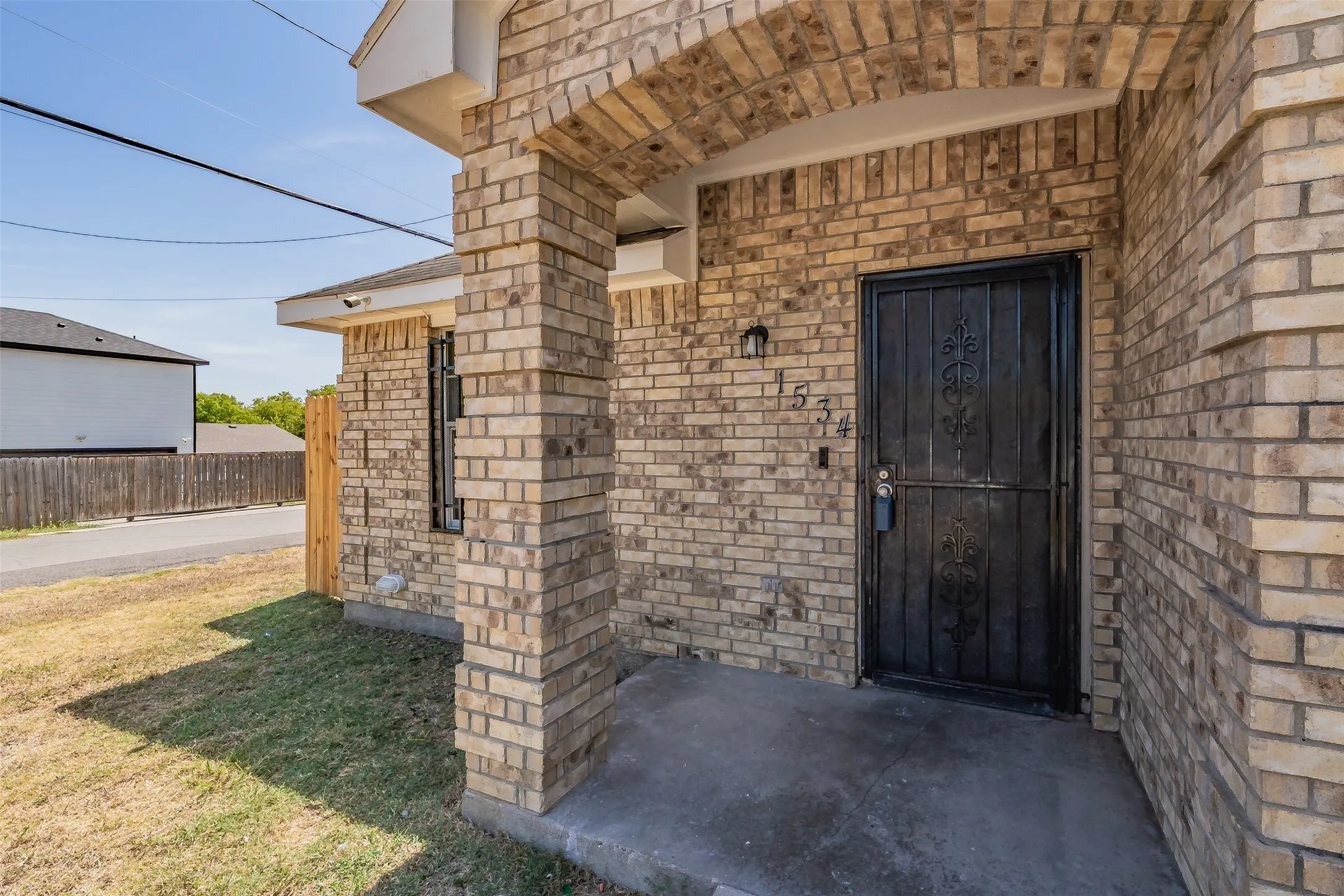 Brick facade entry featuring an arched portico, concrete porch, and black security door